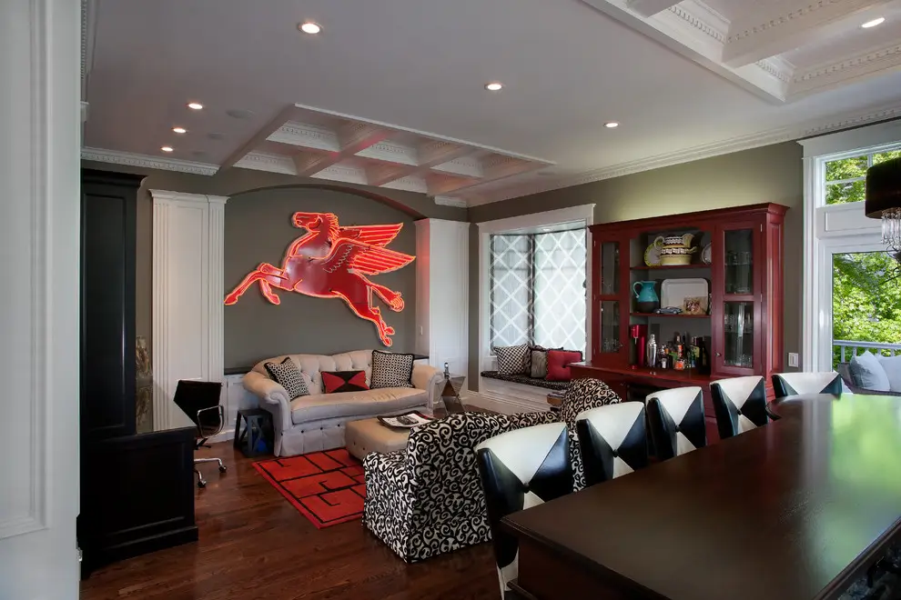 Modern living room with minimalist design features, including a neon Pegasus wall art, a beige sofa with geometric cushions, a black and white patterned chair, and a classic wooden cabinet. The room has a coffered ceiling and large windows offering natural light, complemented by wooden flooring and red accents.