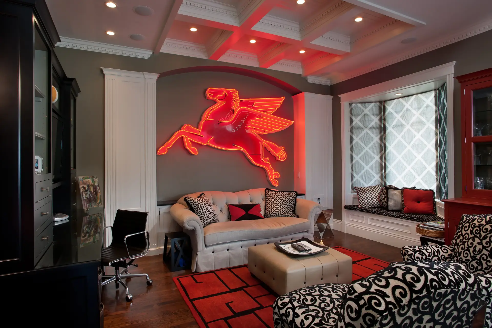 Modern living room with stylish decor featuring a tufted sofa, patterned armchairs, and a prominent red neon Pegasus wall art. The room includes black cabinetry with minimalist shelving, a decorative rug, and elegant lighting.