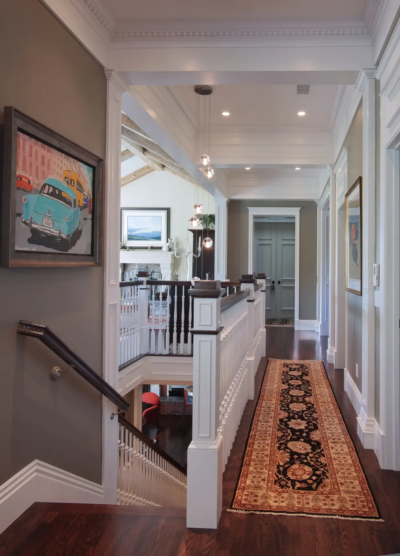 Elegant interior hallway with ornate wood flooring, detailed white banisters, decorative ceiling moldings, and framed artwork, emphasizing classic design el