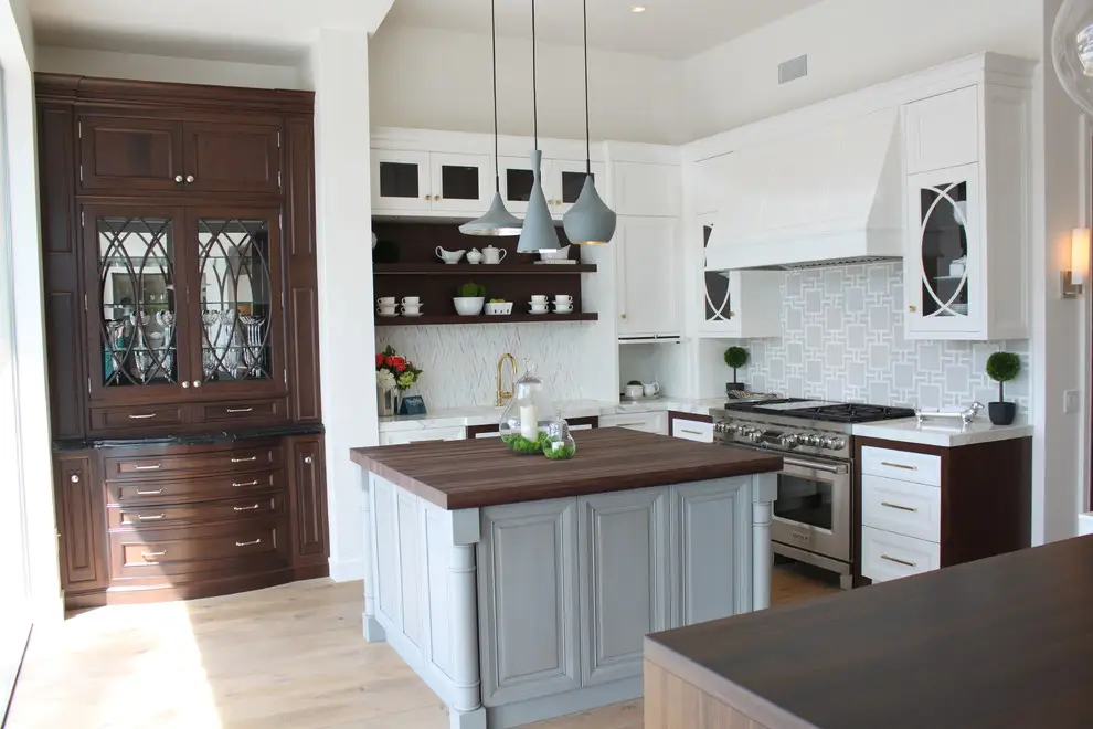 Modern kitchen with custom cabinetry featuring white and dark wood cabinets, geometric backsplash, and central island with hanging pendant lights.