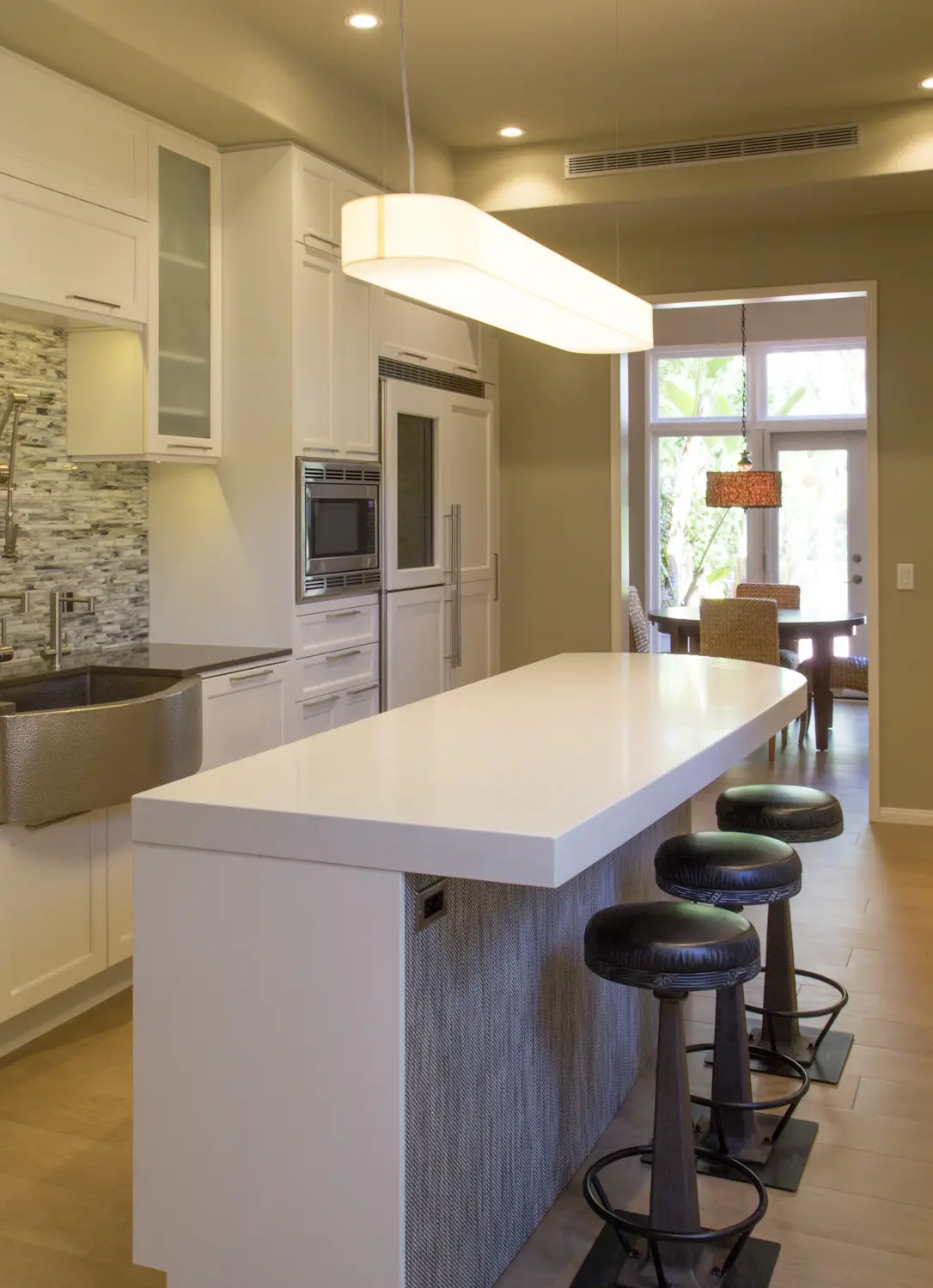 Modern kitchen with custom white cabinetry, a large island with seating, stain