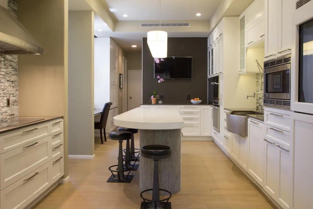 Modern kitchen with custom cabinetry, white cabinets, large island, and seating. Efficient storage solutions and sleek design elements are featured, enhancing contemporary kitchen aesthetics.