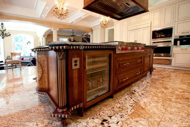 Luxurious kitchen with custom wooden cabinets and a marble island, designed by Inplace Studio. Elegant chandeliers and cream-colored cabinetry complement the high-end appliances, creating a sophisticated cooking space.