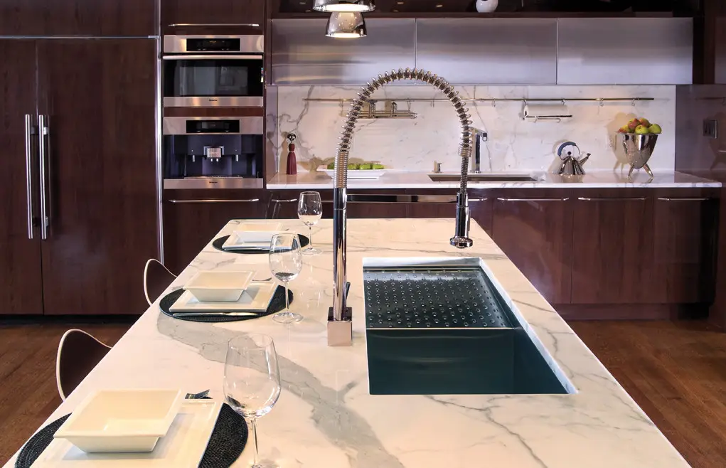 Luxurious modern kitchen with marble countertops and dark wood cabinets, featuring stainless steel appliances and a sleek faucet on the island. Ideal for custom closet and cabinet design inspiration with Inplace Studio.