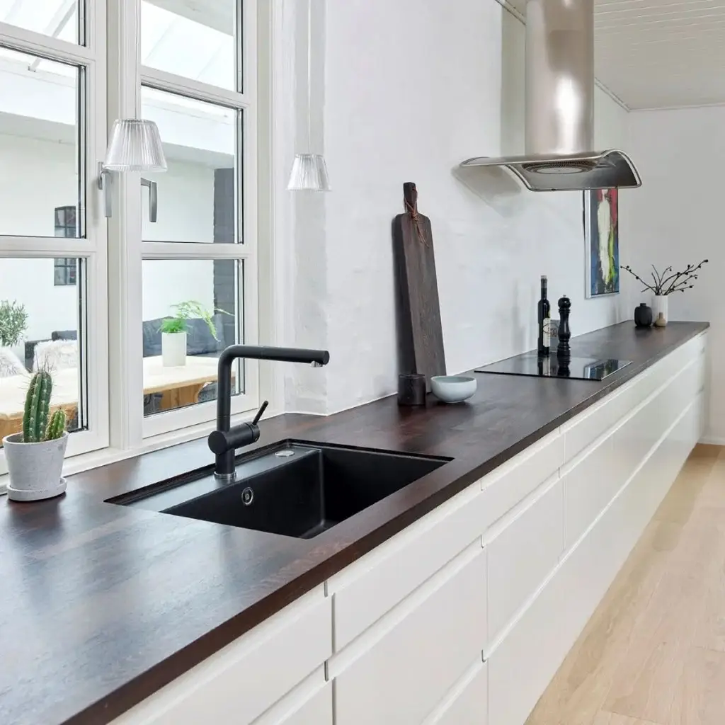 Sleek modern kitchen with custom cabinetry, dark wood countertops, black sink, and minimalist decor, highlighting modern designer kitchen solutions by Inplace Studio.