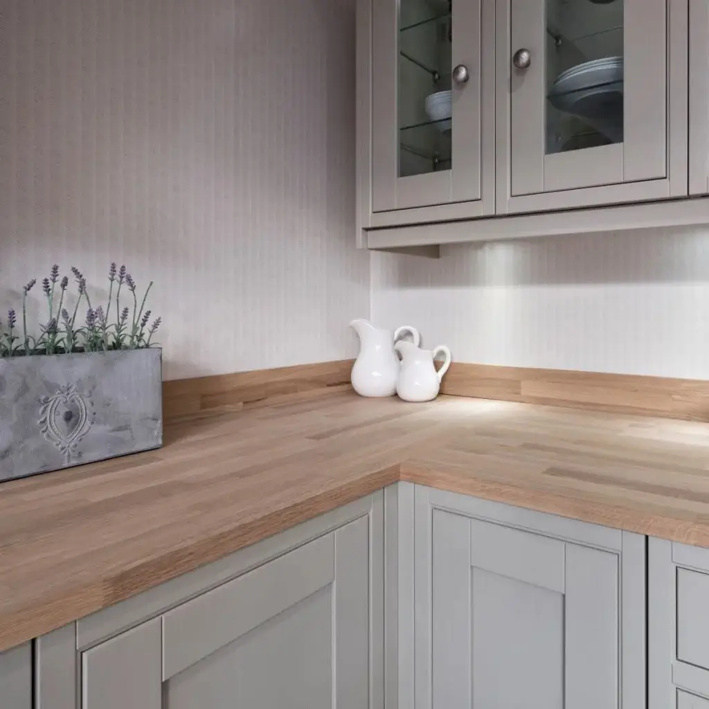 Modern designer kitchen with custom cabinetry by Inplace Studio. Features elegant light-colored wooden countertops, soft grey cabinets, and stylish detailing. Decorative elements include a lavender plant in a textured pot and white ceramic pitchers, enhancing the kitchen's contemporary aesthetic.