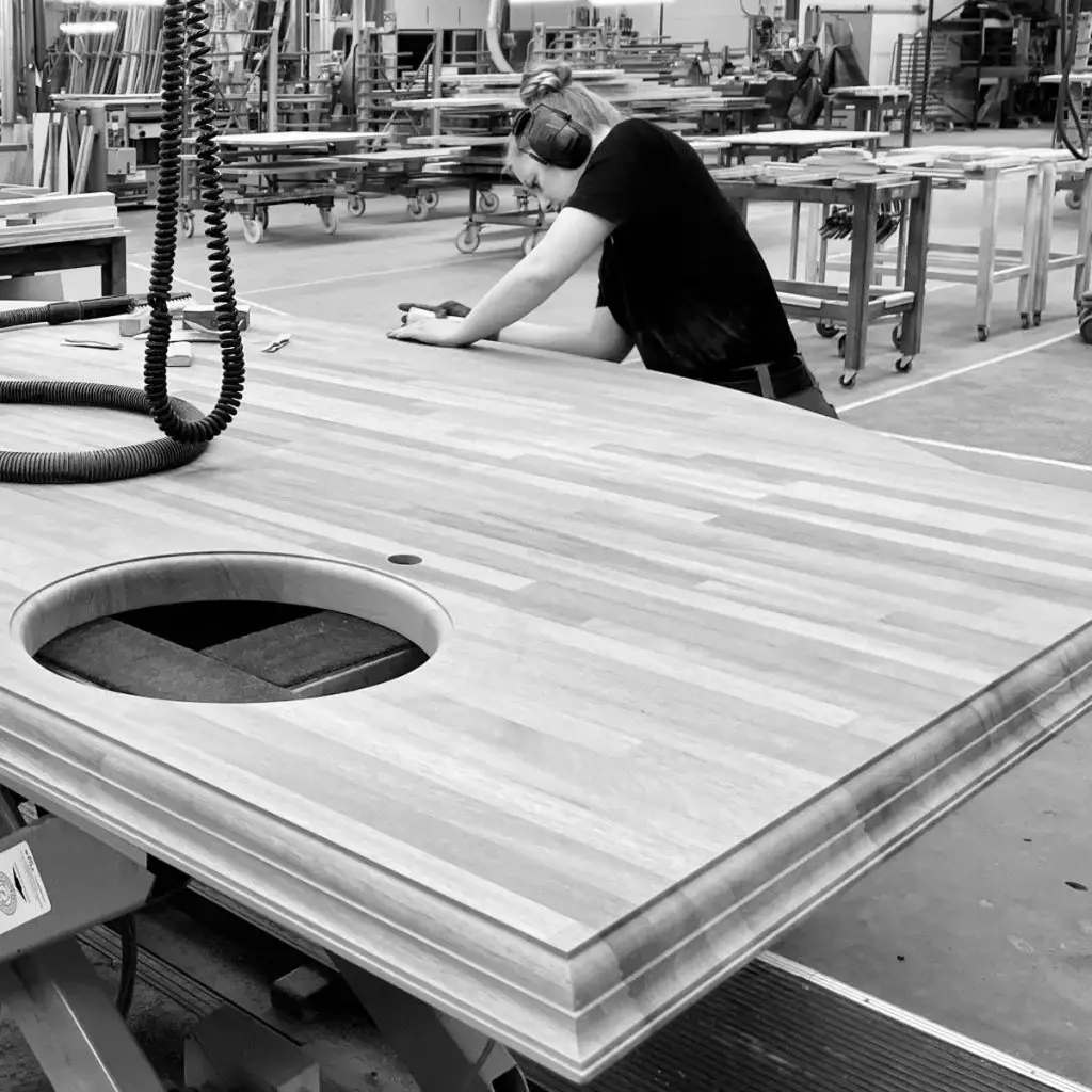 Craftsperson measuring a wooden kitchen countertop in a workshop, showcasing custom kitchen cabinetry and modern kitchen cabinets design.