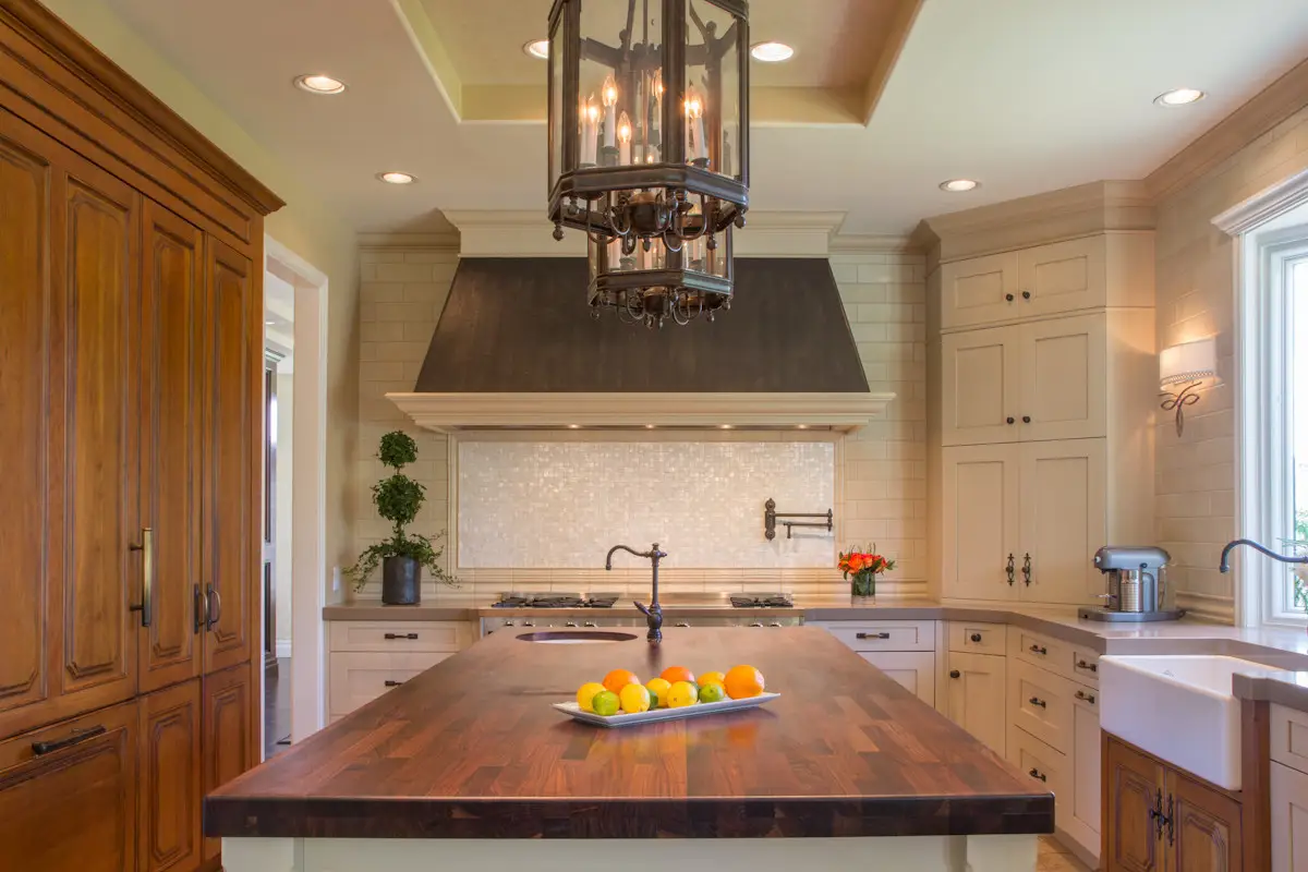 Luxurious kitchen with elegant custom cabinetry, featuring a large wooden island with oranges, modern appliances, and stylish lighting in Los Angeles home.