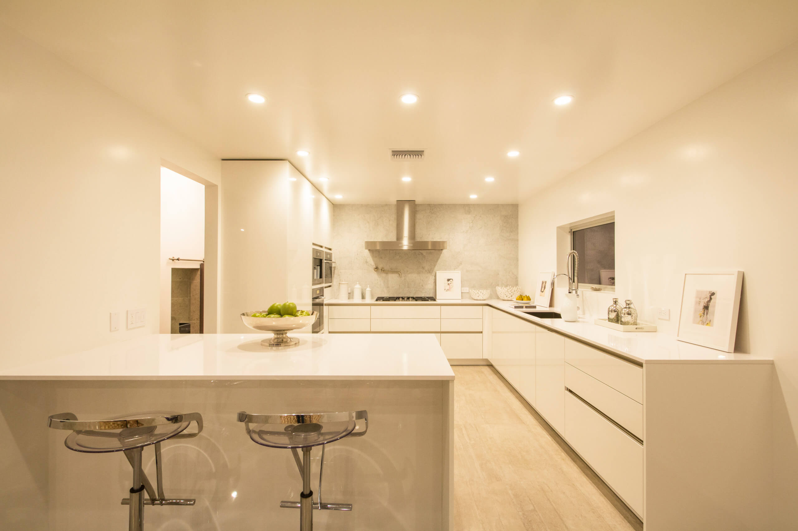 Modern kitchen with sleek custom cabinetry, white countertops, and contemporary lighting in Encinitas home.
