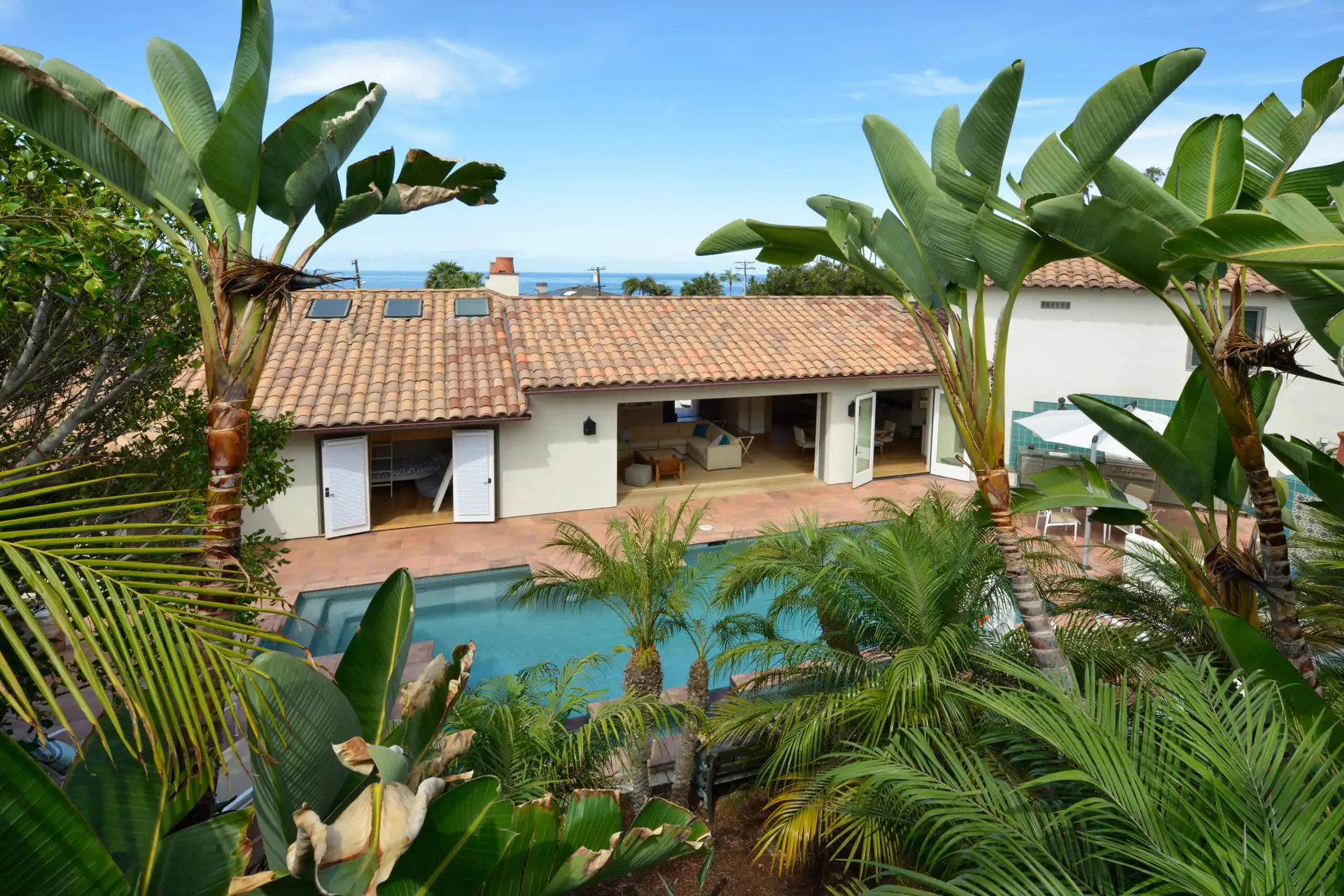 Modern home with tiled roof and open patio doors leading to a swimming pool