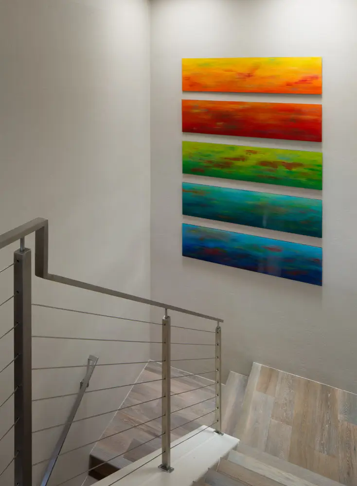 Contemporary staircase with cable railing and colorful abstract artwork on the wall