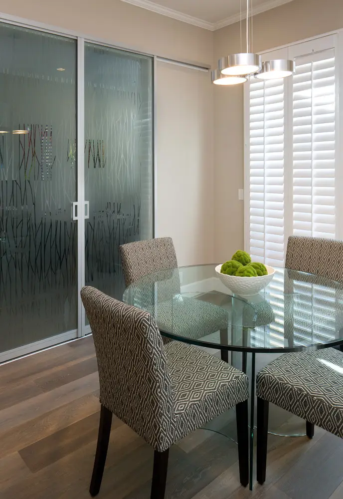 Modern dining area featuring a glass-top round table surrounded by patterned upholstered chairs