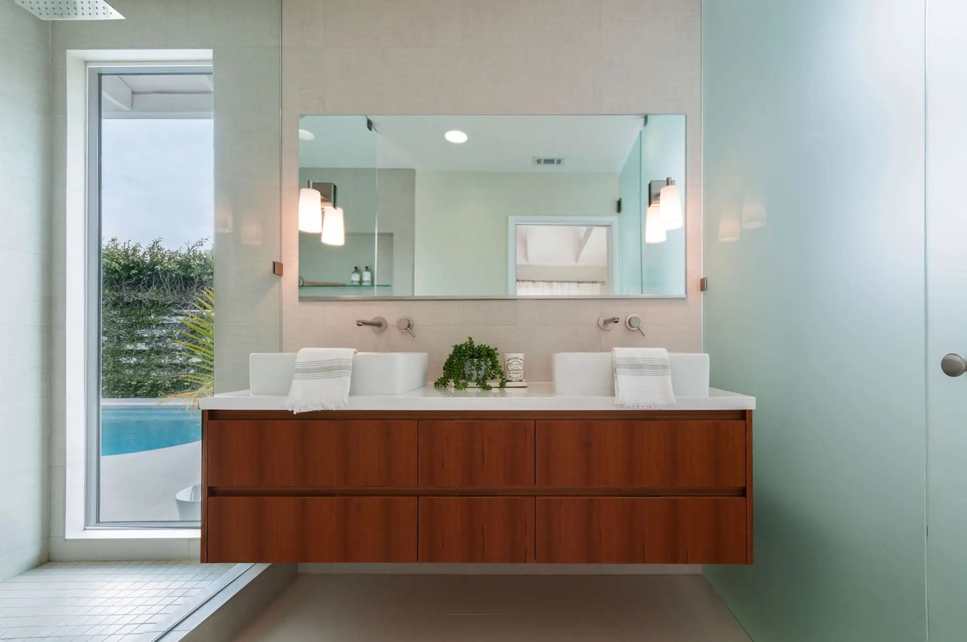 Modern bathroom with sleek wooden cabinets, dual sinks, and a large mirror, featuring minimalistic design elements and soft ambient lighting, enhancing elegant space aesthetics.