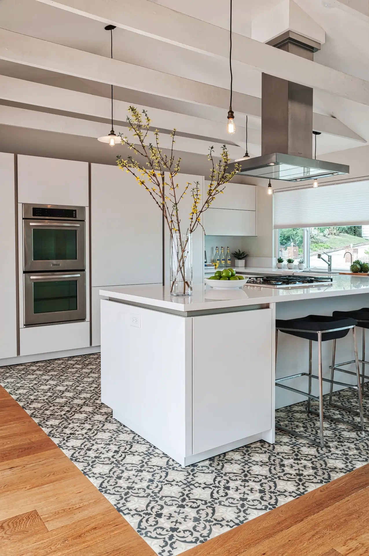 Modern luxury kitchen featuring sleek white cabinets, a central island with decorative tile flooring, stainless steel appliances, and minimalist decor for elegant spaces.