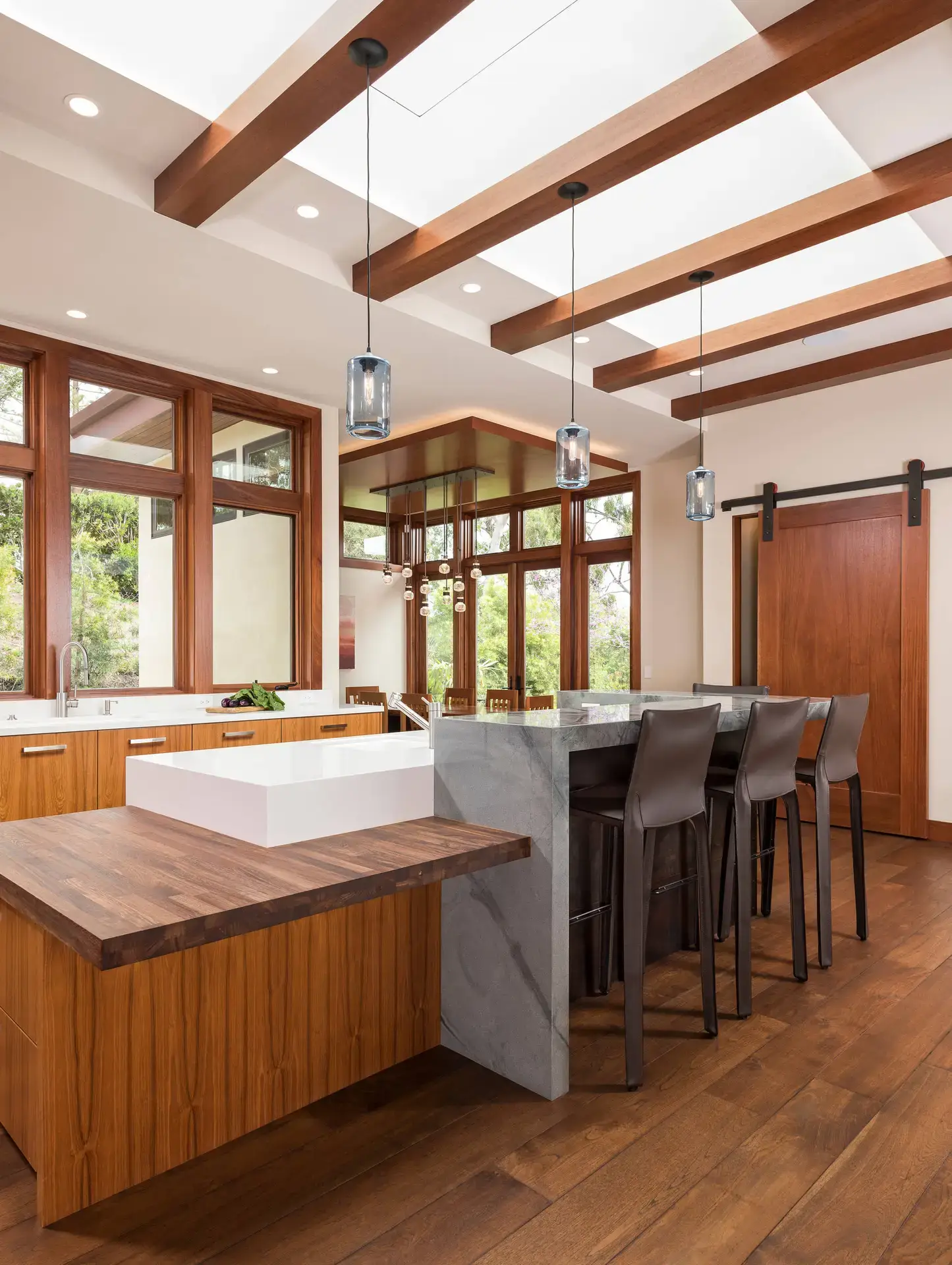 Luxurious custom kitchen design featuring wood cabinetry, marble countertops, and high-end bar stools in a modern San Diego home setting.