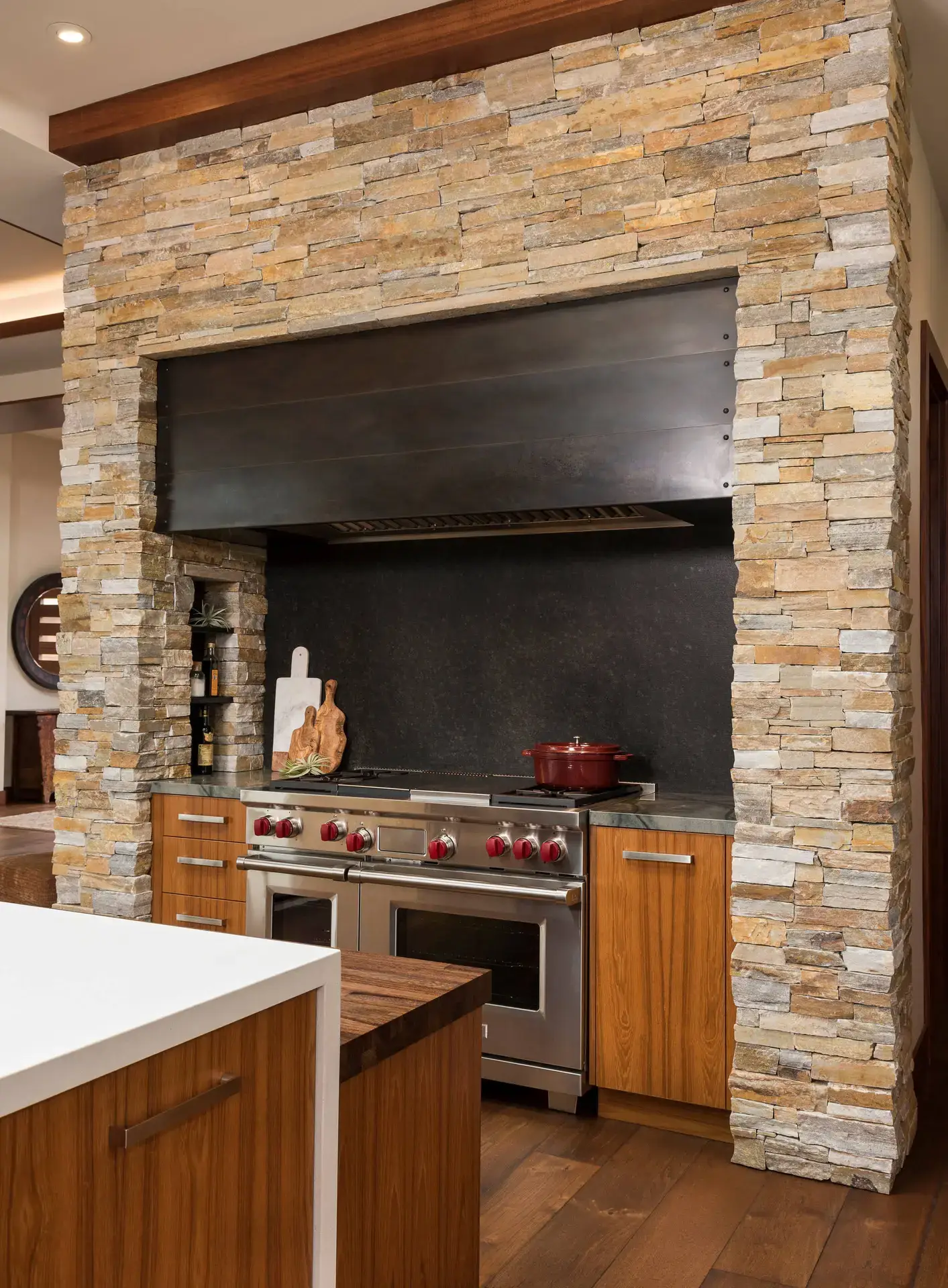 Luxury kitchen with high-end custom cabinetry featuring natural stone wall accents, modern stainless steel oven, and elegant wooden cabinets in San Diego & LA.
