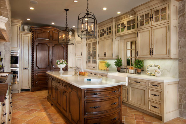 Luxury kitchen remodel featuring custom cabinetry with a blend of dark wood and distressed white finishes. Central island with polished countertop, decorative pendant lights, and terracotta tile flooring. Modern kitchen storage solutions and elegant design elements.