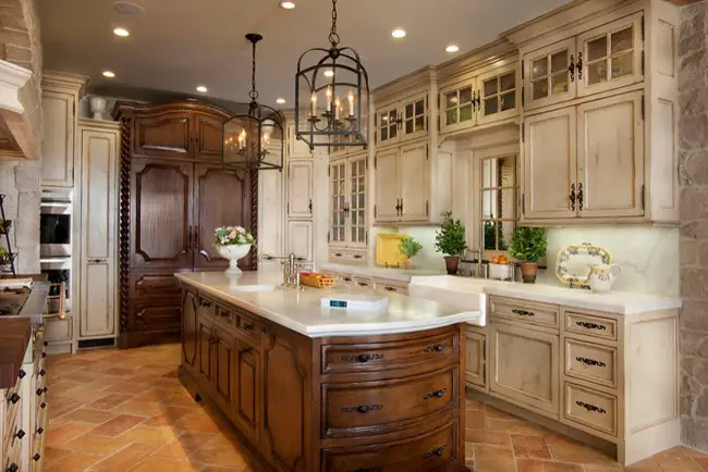 Luxury kitchen remodel featuring custom cabinetry with a blend of dark wood and distressed white finishes. Central island with polished countertop, decorative pendant lights, and terracotta tile flooring. Modern kitchen storage solutions and elegant design elements.