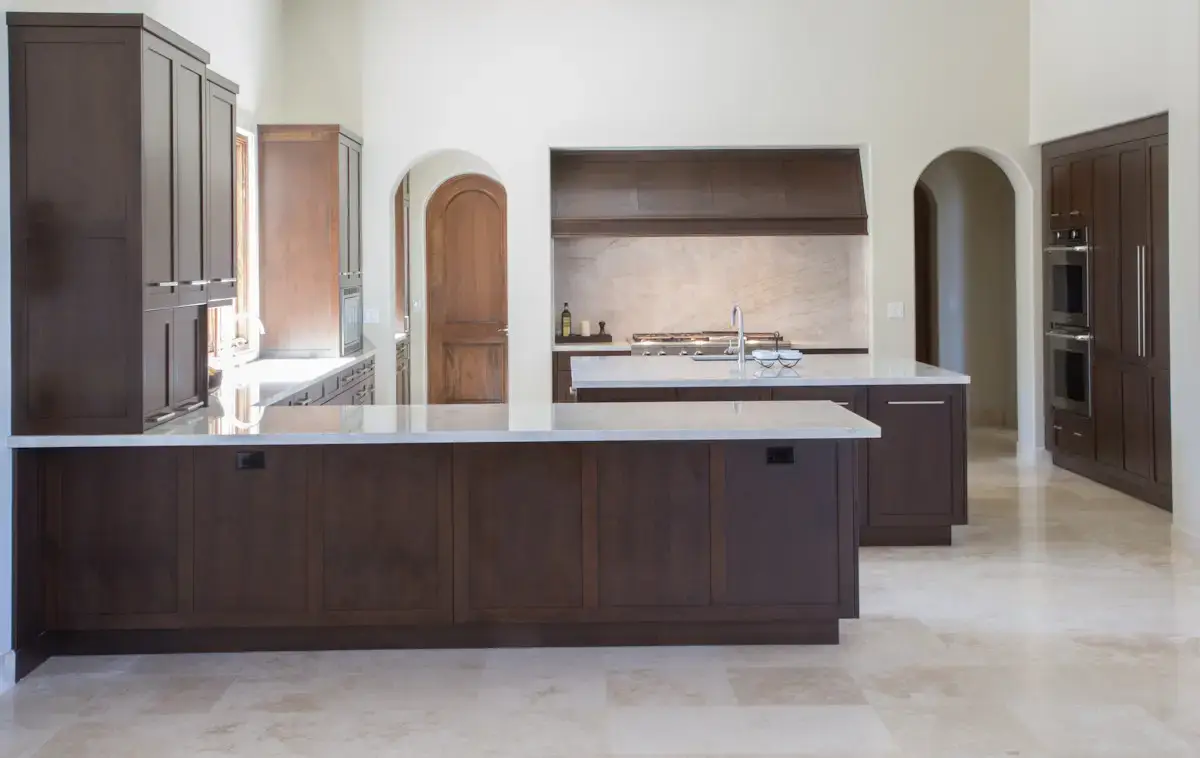 Modern kitchen with custom dark wood cabinets and drawers, marble countertops, and stainless steel appliances, emphasizing home storage solutions.