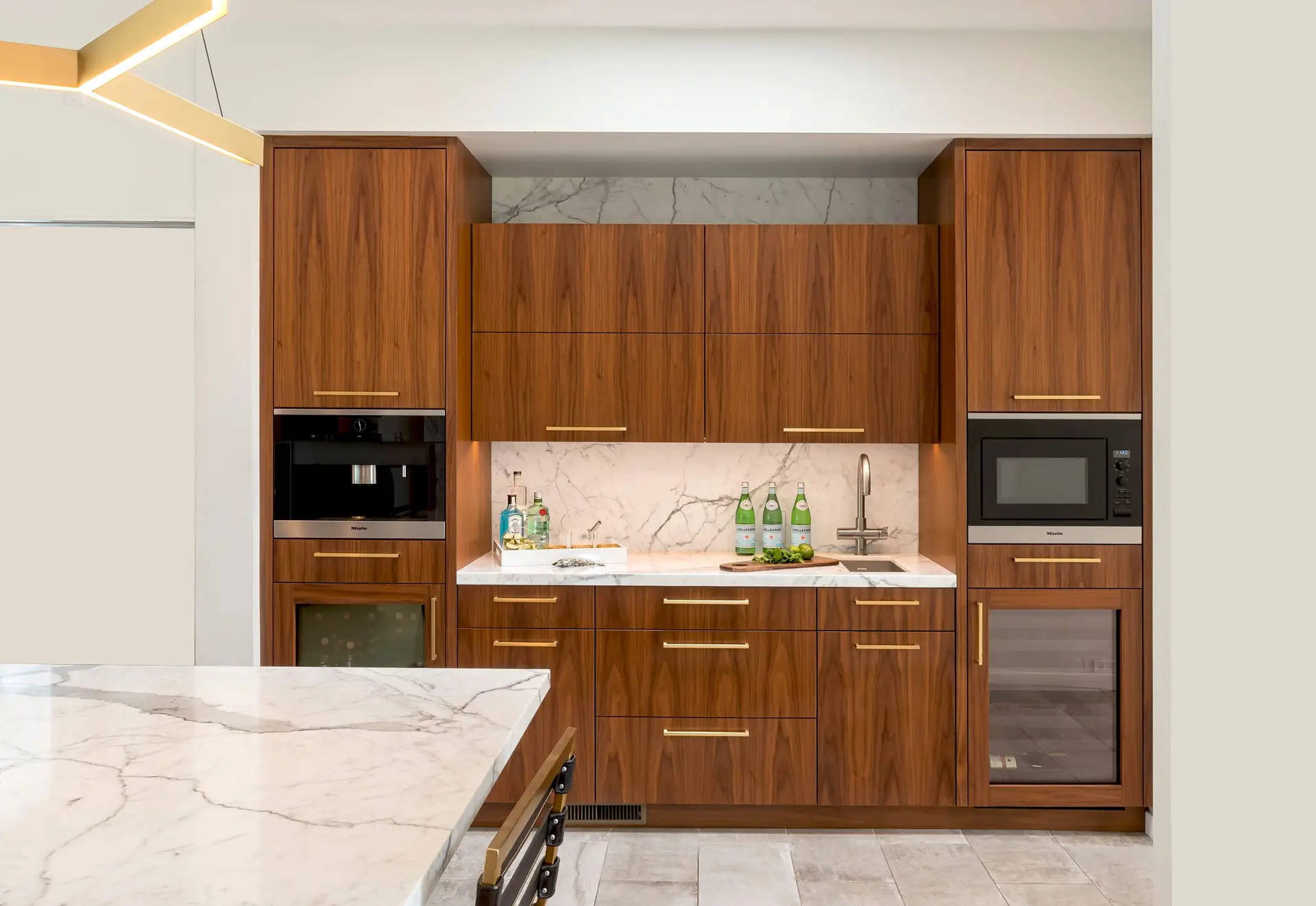 Luxurious custom kitchen cabinetry with wood finish and marble countertops featuring modern appliances, designed for stylish storage solutions.