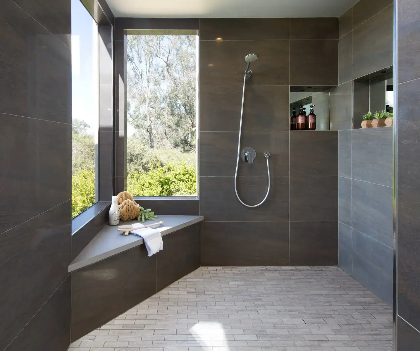 Modern European bathroom with sleek dark tiles, large windows offering natural light and greenery view, minimalistic shower design, and elegant bath accessories emphasizing luxury interior solutions.