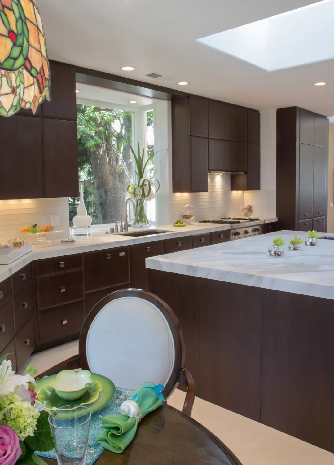 Modern luxury kitchen featuring custom dark wood cabinetry, marble countertops, and elegant lighting. A