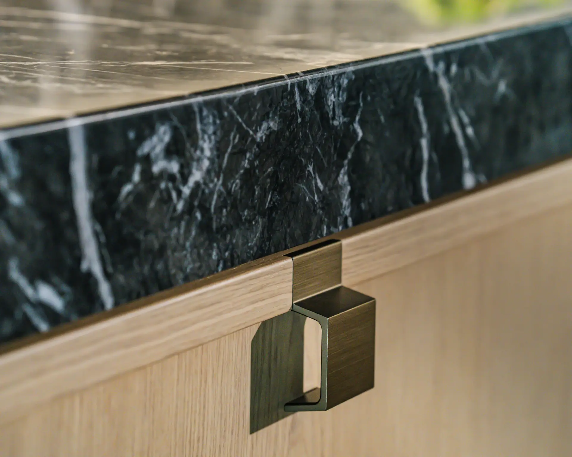 SieMatic MONDIAL detail &mdash; green marble countertop edge with bronze grip on oak