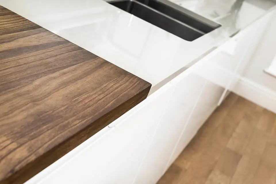 Close-up of a modern kitchen countertop featuring a wooden section and integrated sink, showcasing luxury design and high-quality cabinetry.