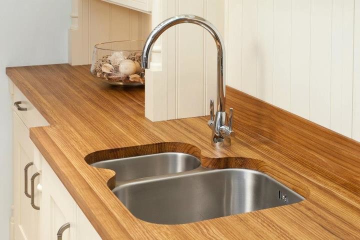 Luxury kitchenette with custom wooden countertop and modern stainless steel sink. Elegant cabinetry complements the design for a sophisticated space.