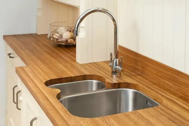Luxury kitchenette with custom wooden countertop and modern stainless steel sink. Elegant cabinetry complements the design for a sophisticated space.