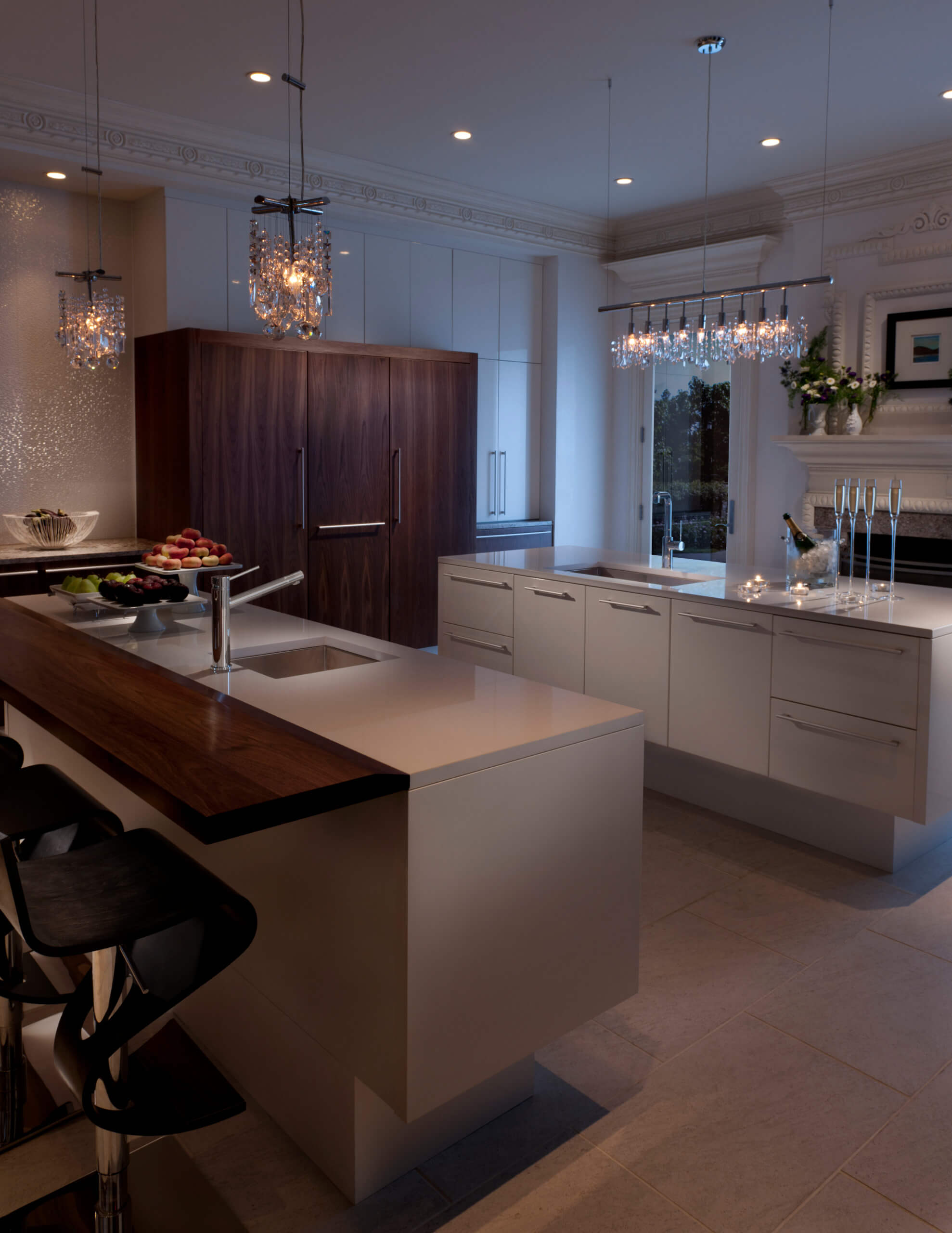 Luxurious kitchen design featuring modern transitional cabinetry, elegant crystal pendant lighting, and a chic combination of dark wood and light countertop surfaces, creating a sophisticated ambiance.
