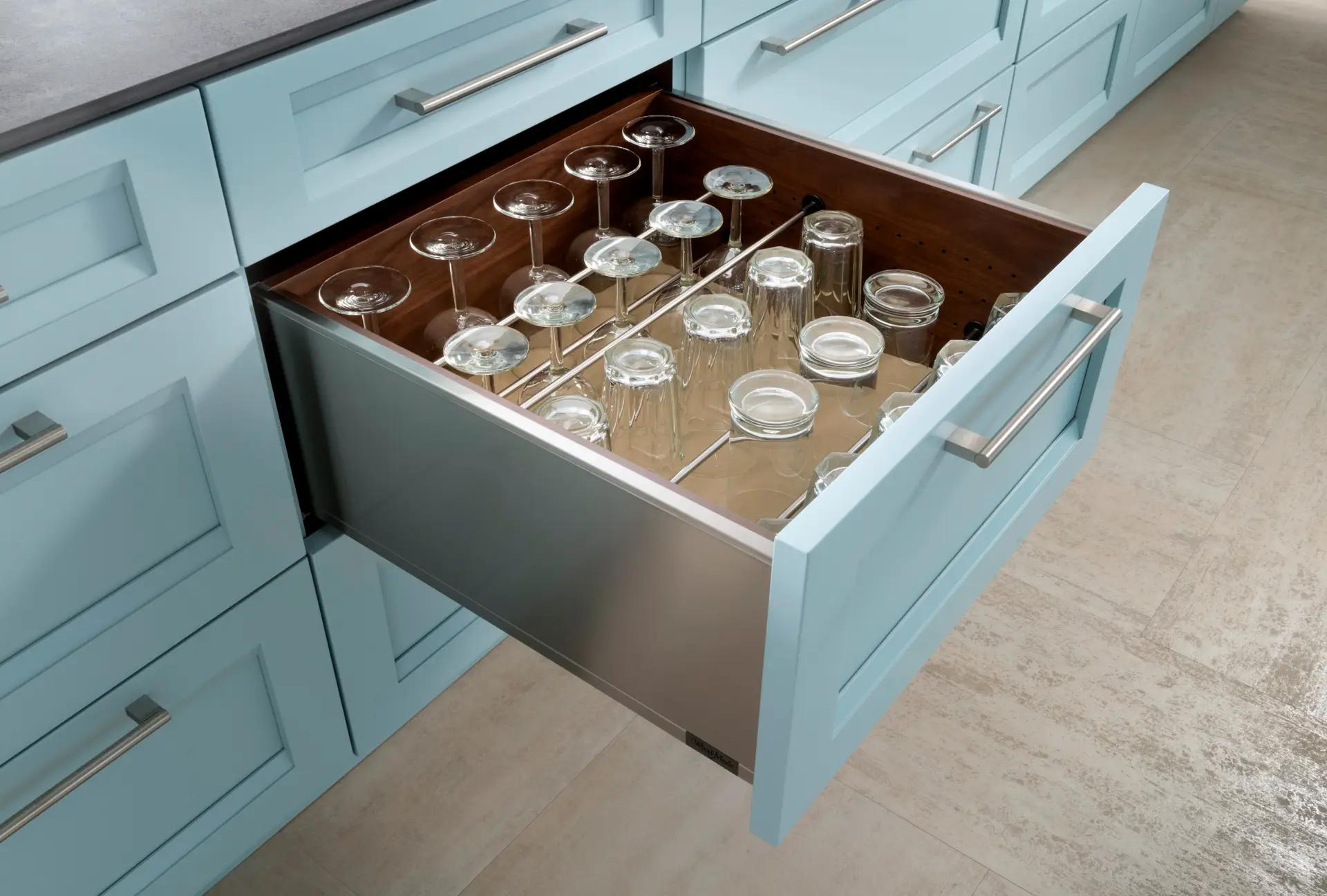 Custom light blue kitchen cabinetry with an open drawer showcasing organized glassware storage in San Diego.