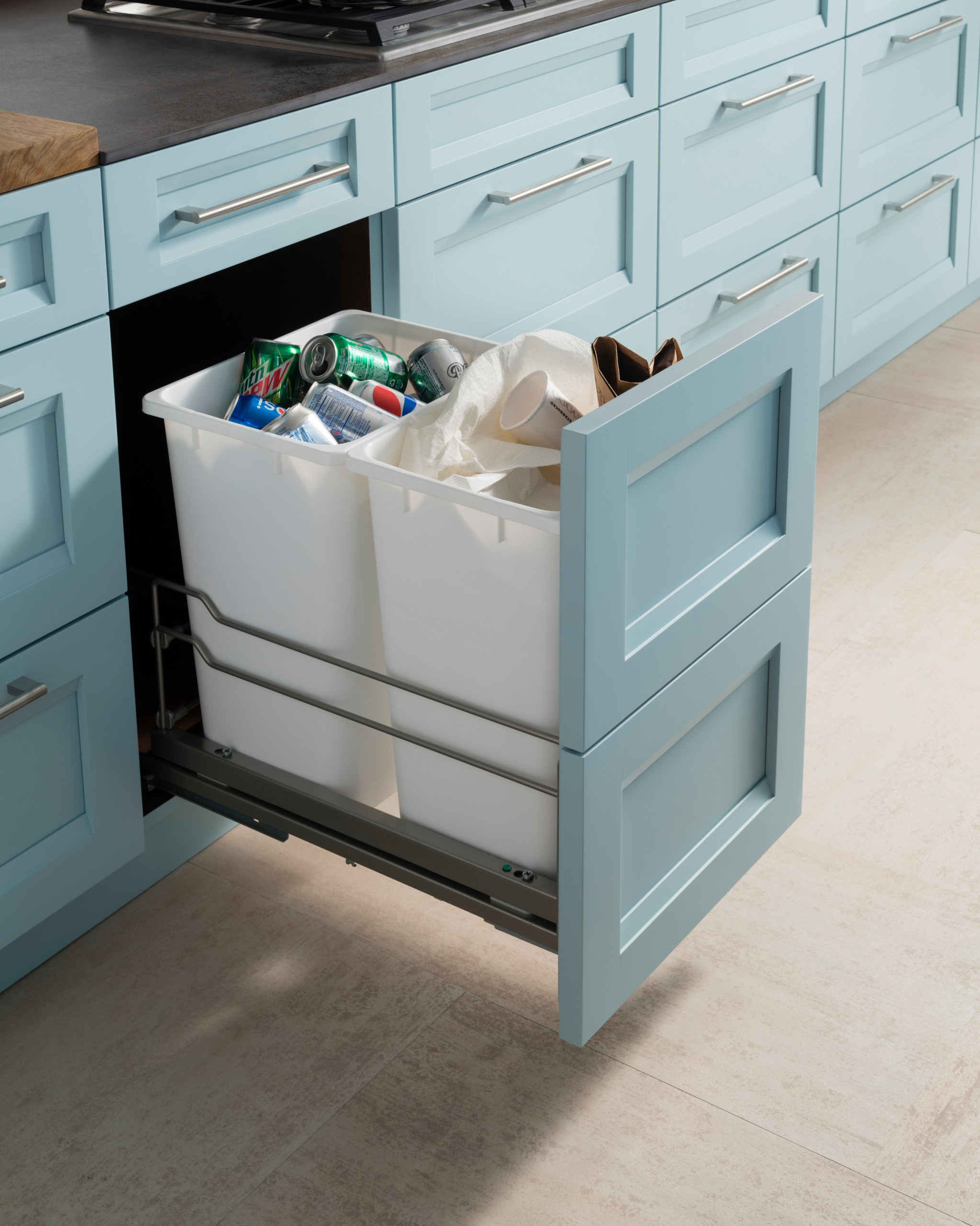 Light blue custom kitchen cabinetry with pull-out trash storage, showcasing elegant design and functional space organization in San Diego.