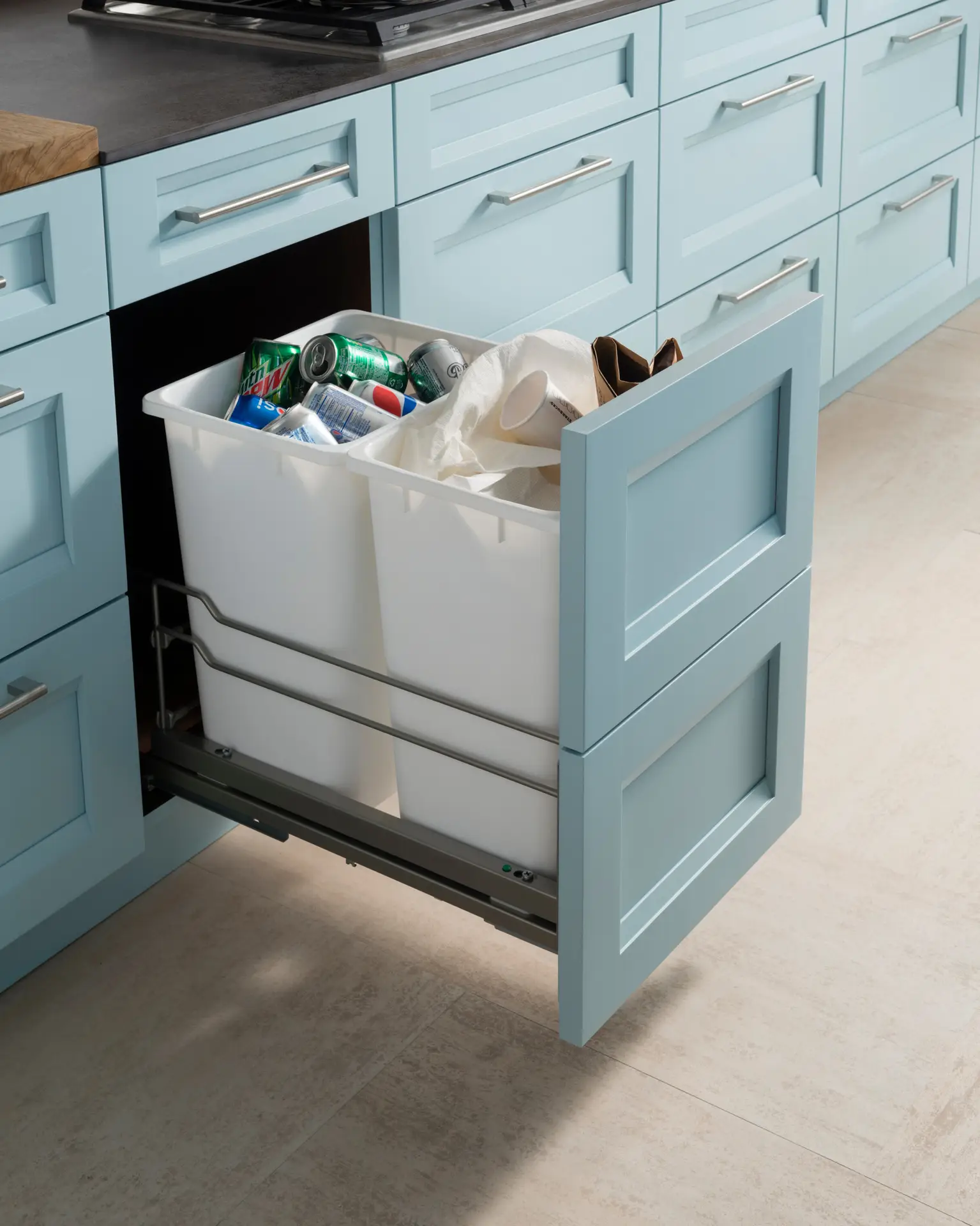 Light blue custom kitchen cabinetry with pull-out trash storage, showcasing elegant design and functional space organization in San Diego.