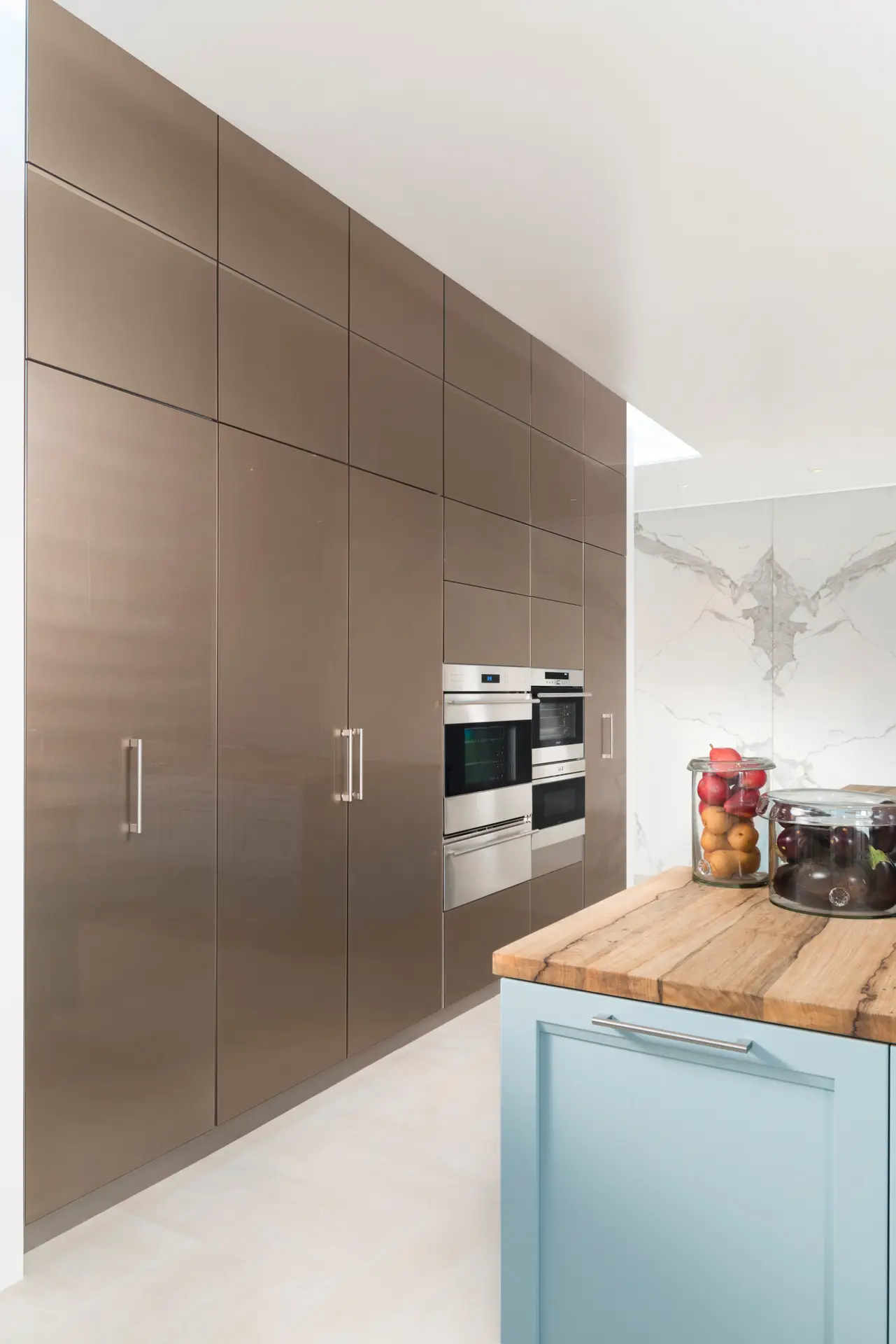 Modern kitchen with custom brown cabinetry featuring built-in stainless steel appliances and a wooden countertop island, showcasing expert cabinetry design in San Diego.