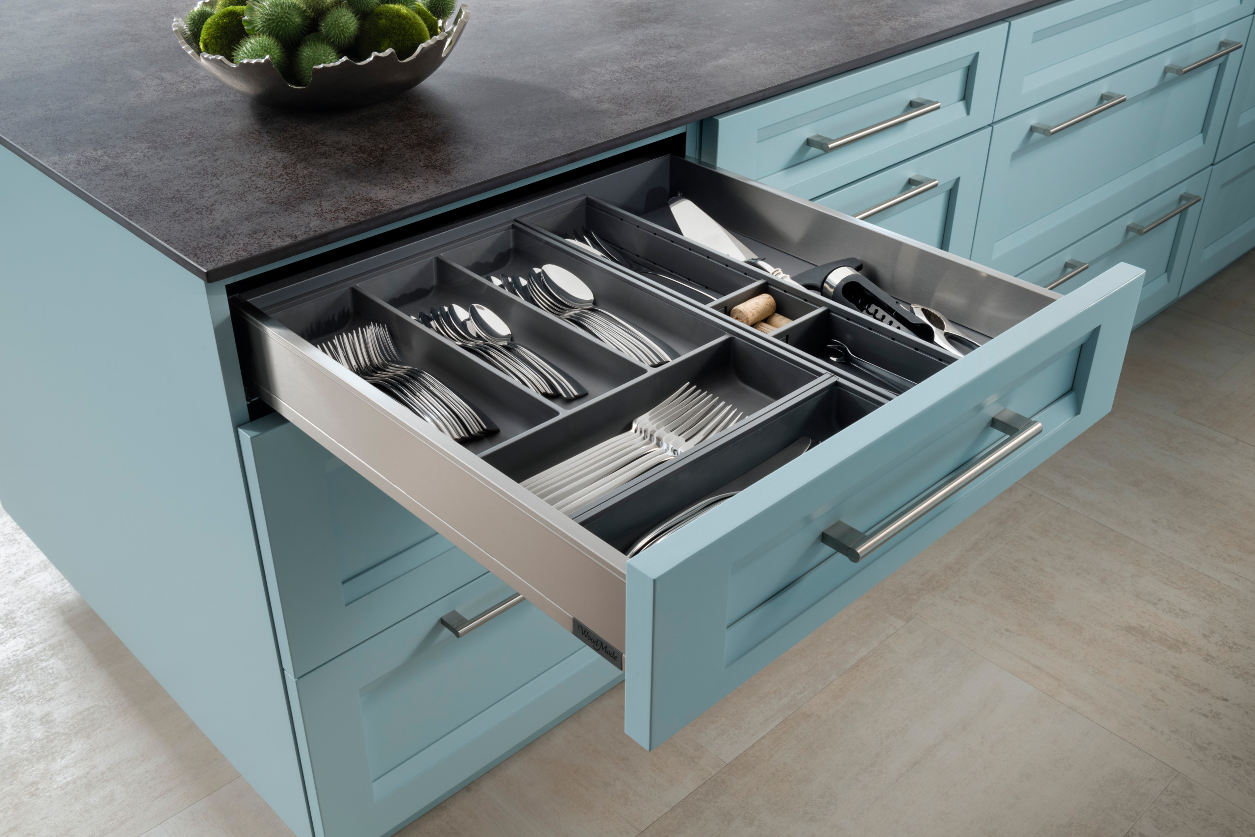 Open blue kitchen cabinet drawer with organized cutlery and utensils, showcasing expert custom cabinetry and elegant storage solutions in San Diego.