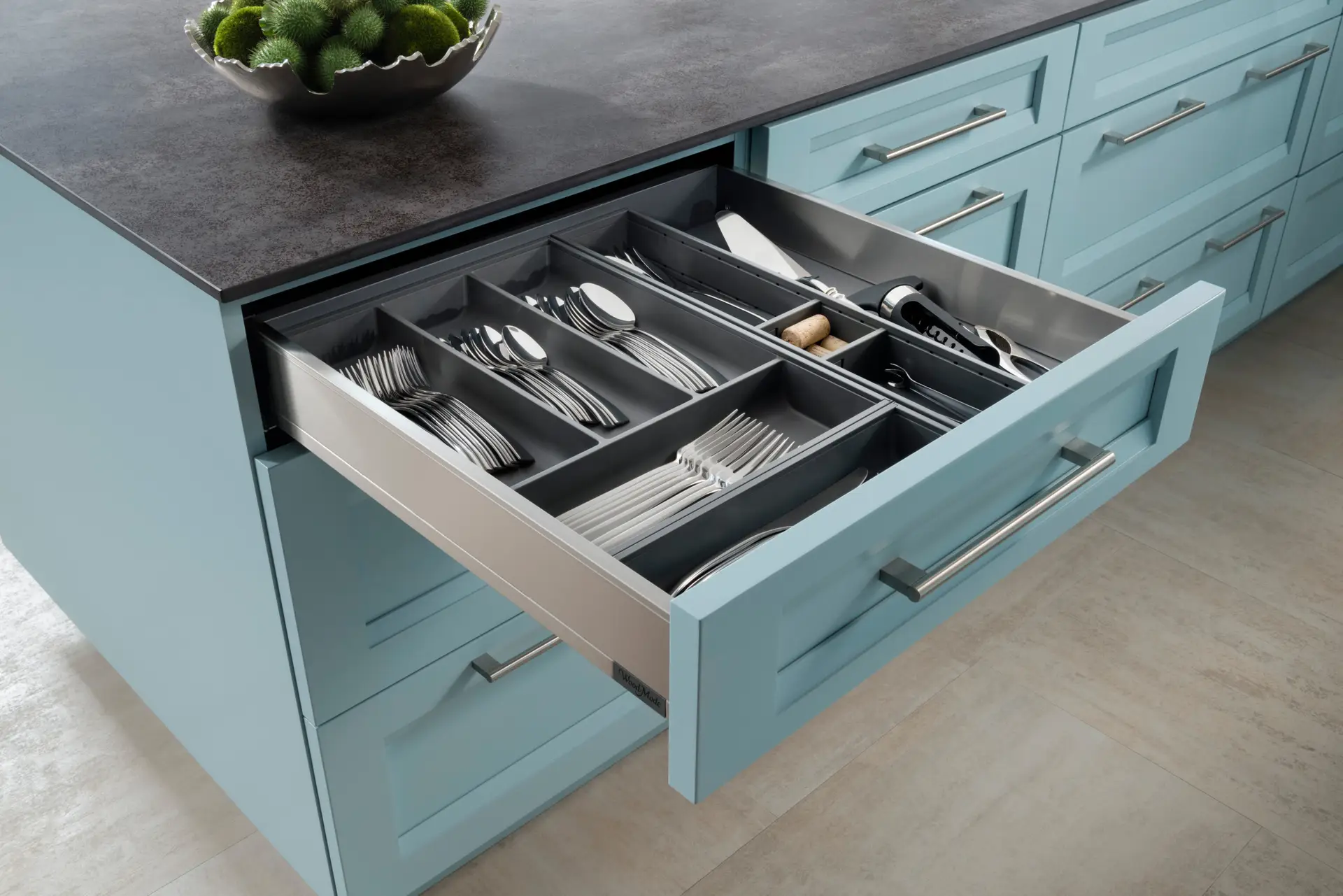 Open blue kitchen cabinet drawer with organized cutlery and utensils, showcasing expert custom cabinetry and elegant storage solutions in San Diego.