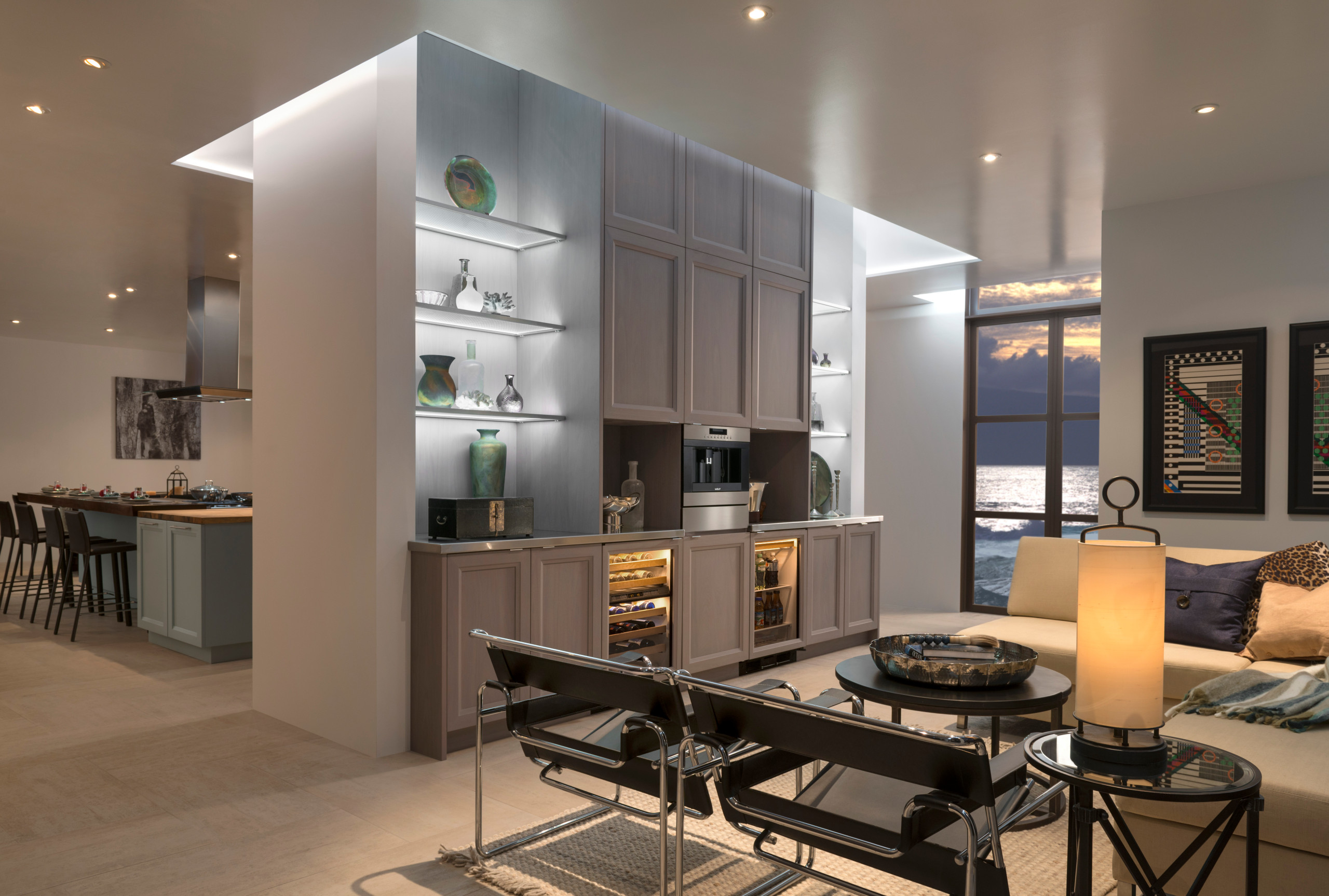 Luxurious open-concept living space with custom cabinetry featuring elegant display shelves and integrated wine storage, located in a modern San Diego home with ocean view.