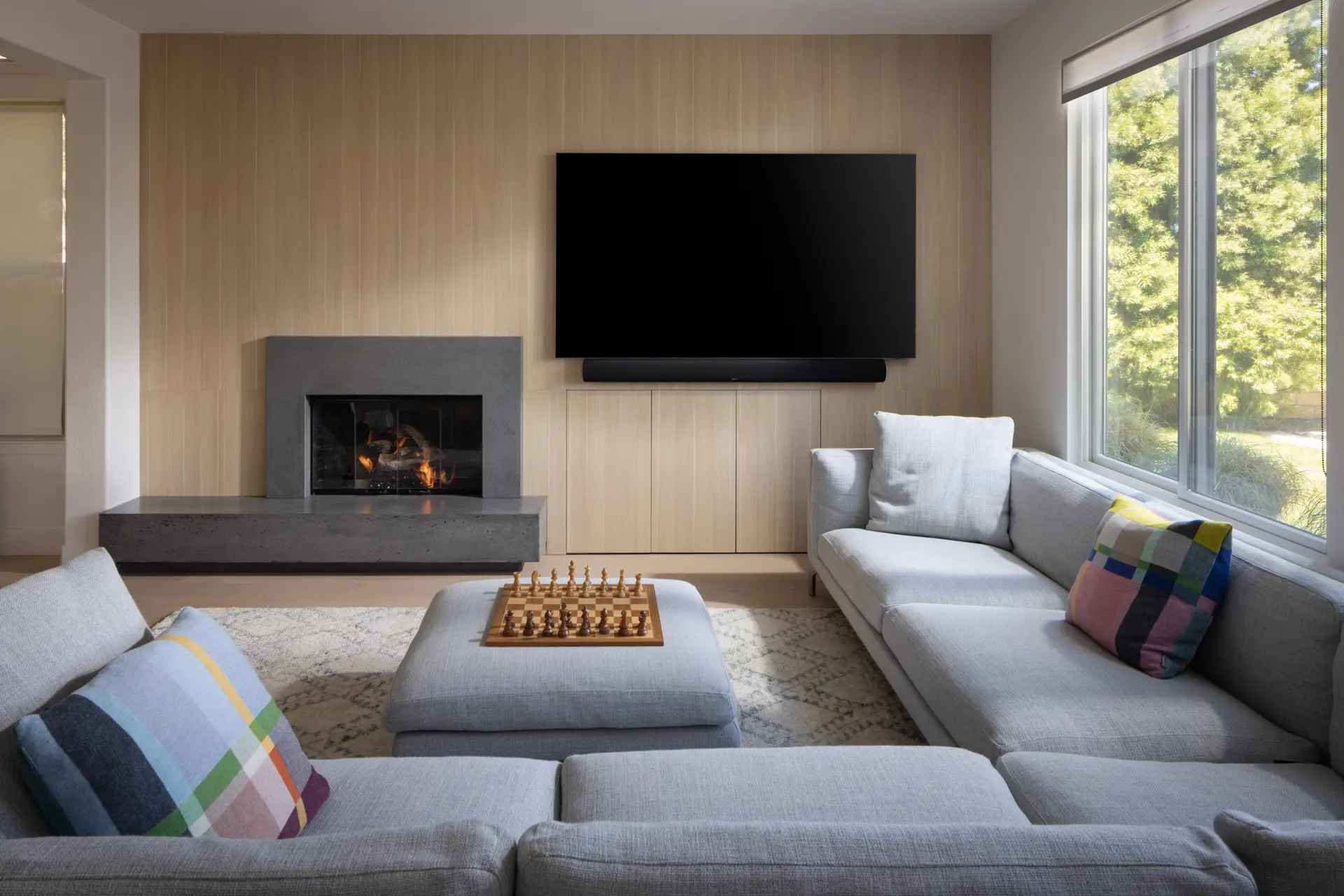 Media wall with custom light oak paneling, concrete fireplace surround and floating hearth bench by Inplace Studio