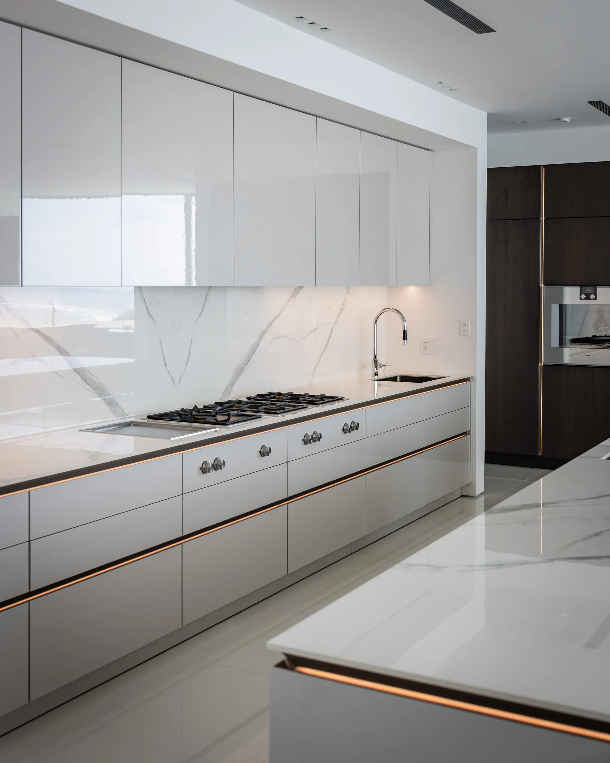 Gas cooktop run with bronze-accent drawer edges and white gloss SieMatic cabinetry