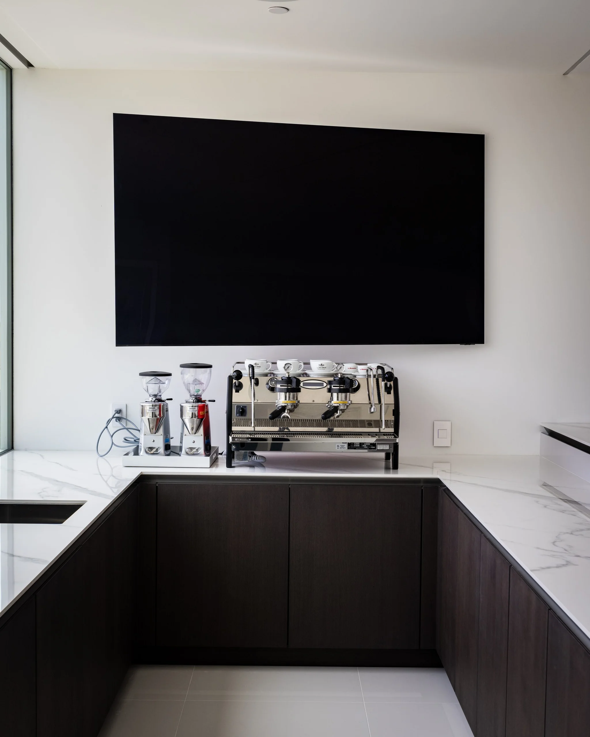 Coffee bar with espresso machines, dark wood base cabinets and white quartz counter