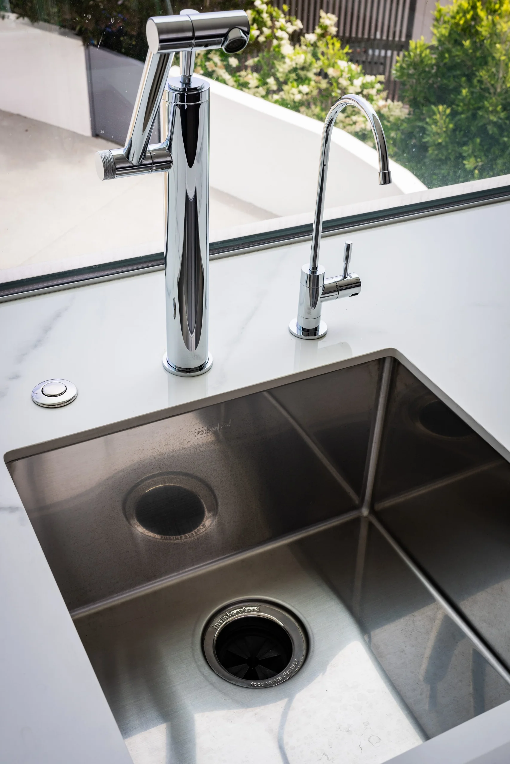 Stainless undermount sink with chrome faucet and filtered-water tap beside an open window