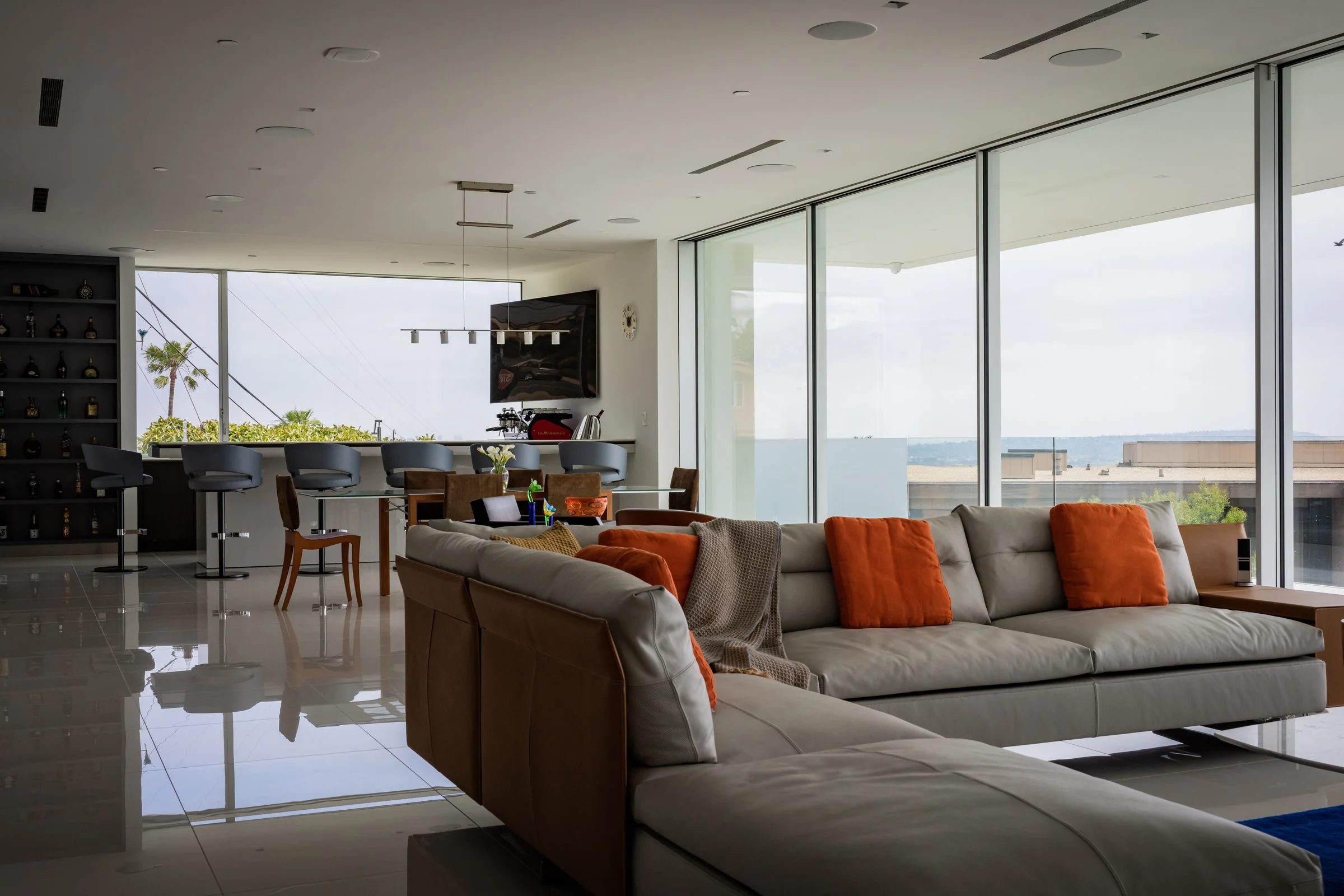 Open living area with leather sectional, bar seating and wine wall beside the SieMatic kitchen