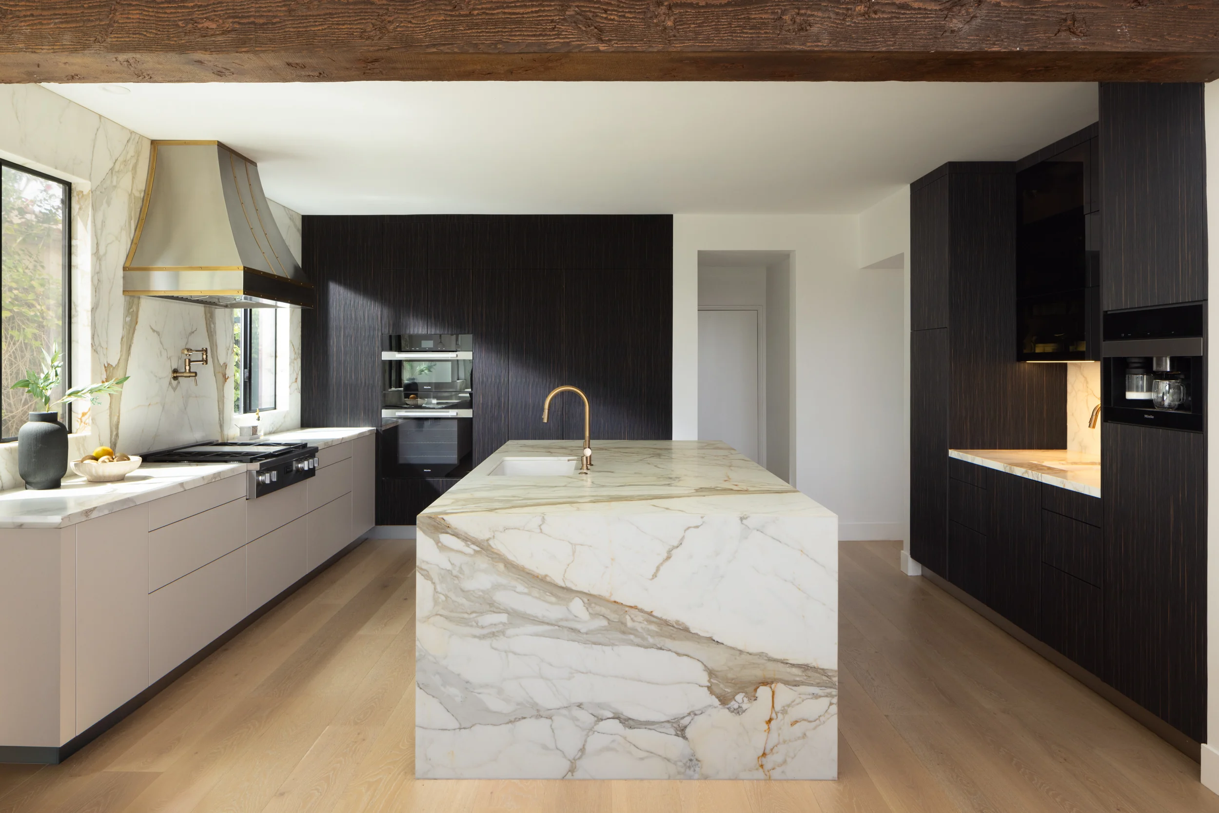 Modern kitchen with a Calacatta marble waterfall island and ebony cabinetry
