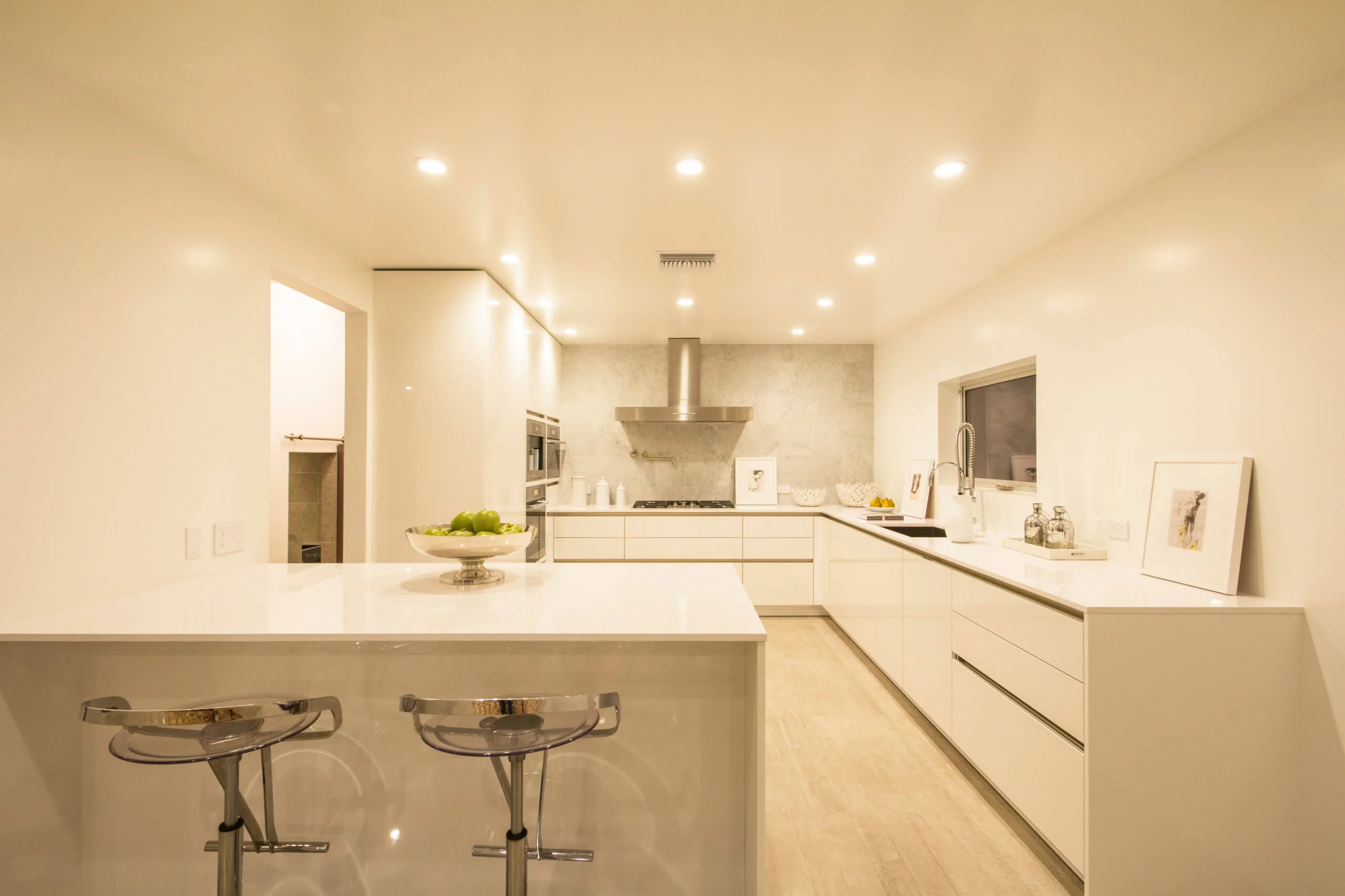 Modern kitchen with sleek custom cabinetry, white countertops, and contemporary lighting in Encinitas home.