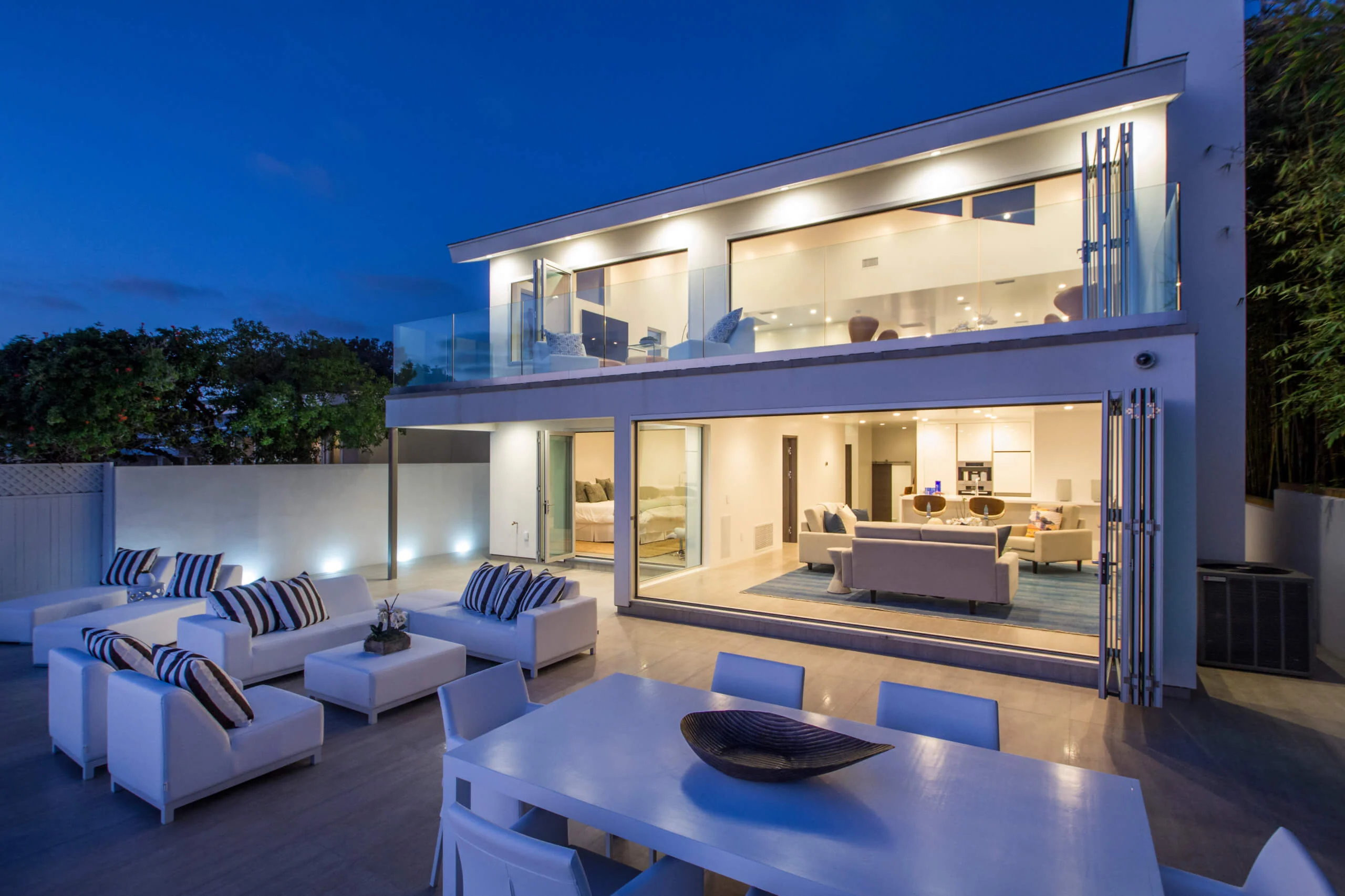 Modern luxury home exterior with spacious outdoor seating area during twilight