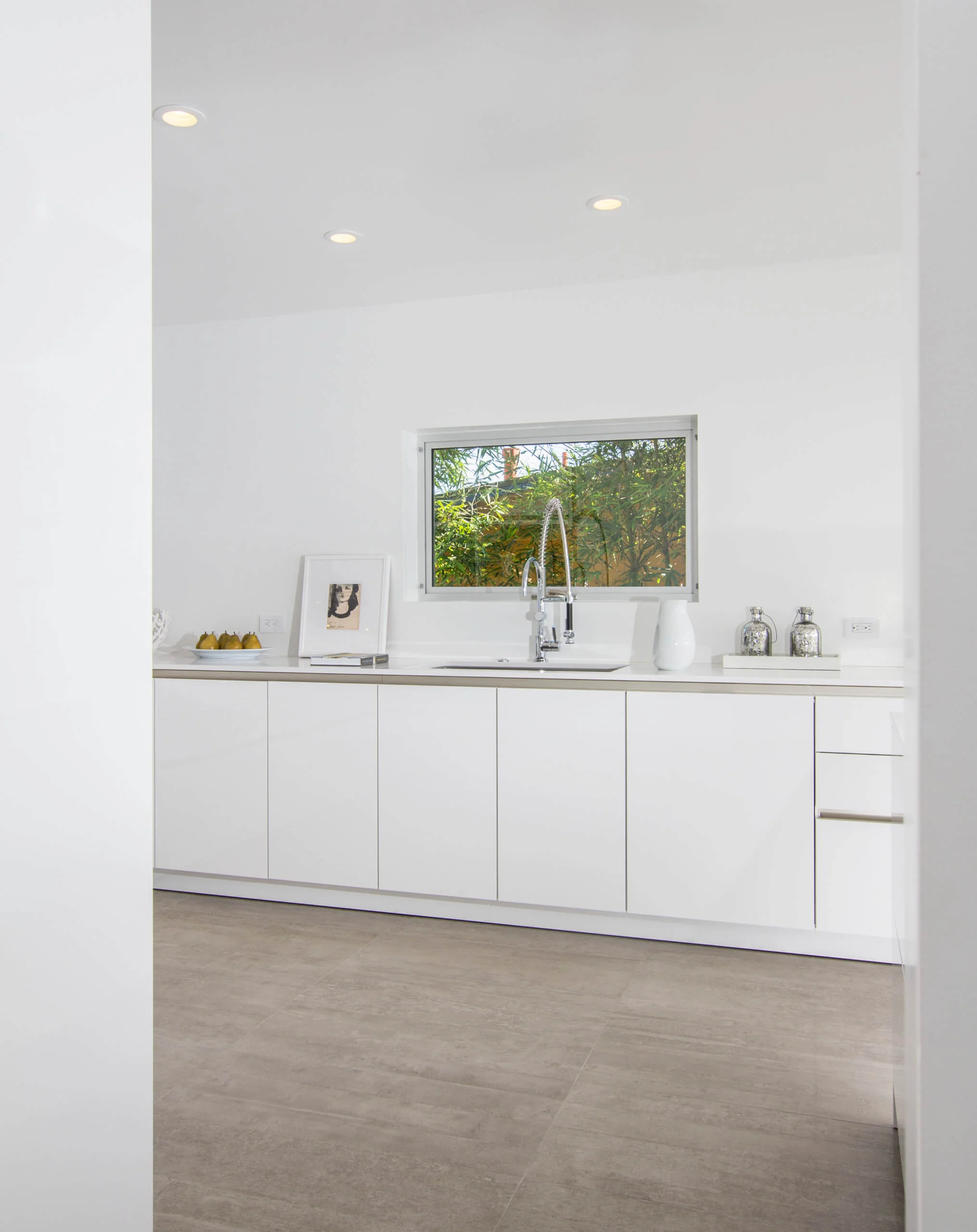Modern white kitchen with sleek custom cabinets and a large window