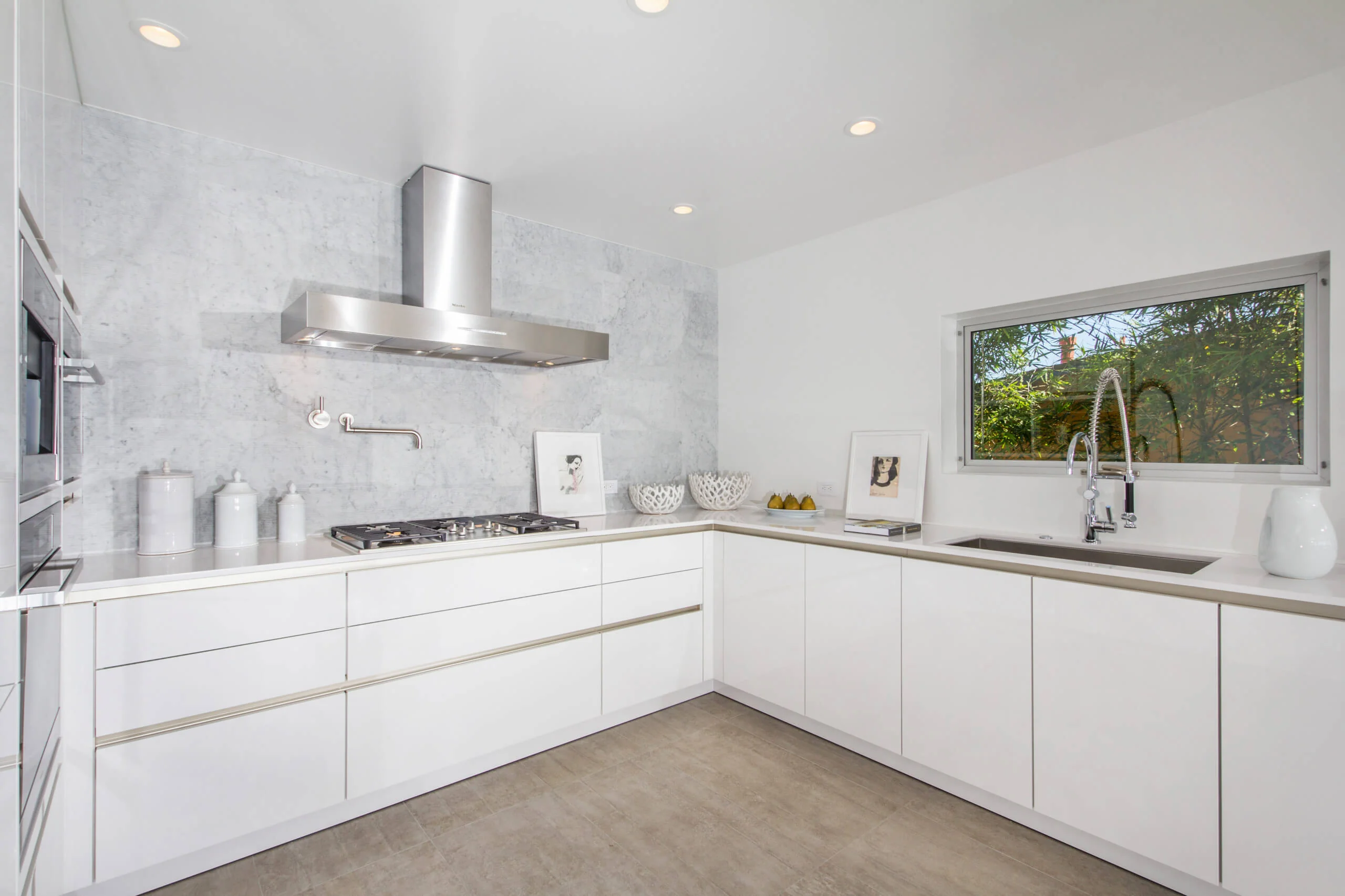 Modern white kitchen with premium custom cabinets in Encinitas, featuring sleek cabinetry, a stainless steel range hood
