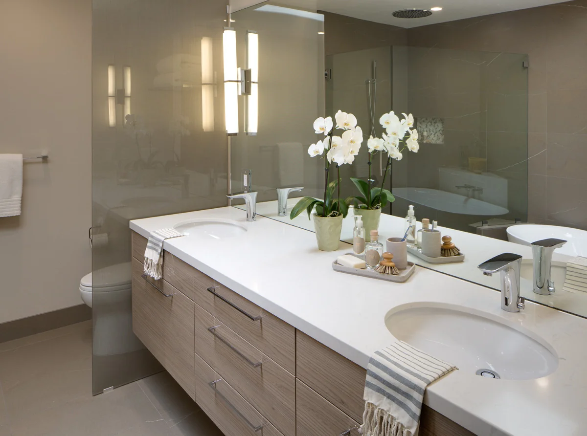 Modern bathroom with custom cabinetry featuring a sleek vanity topped with elegant white countertops and dual sinks