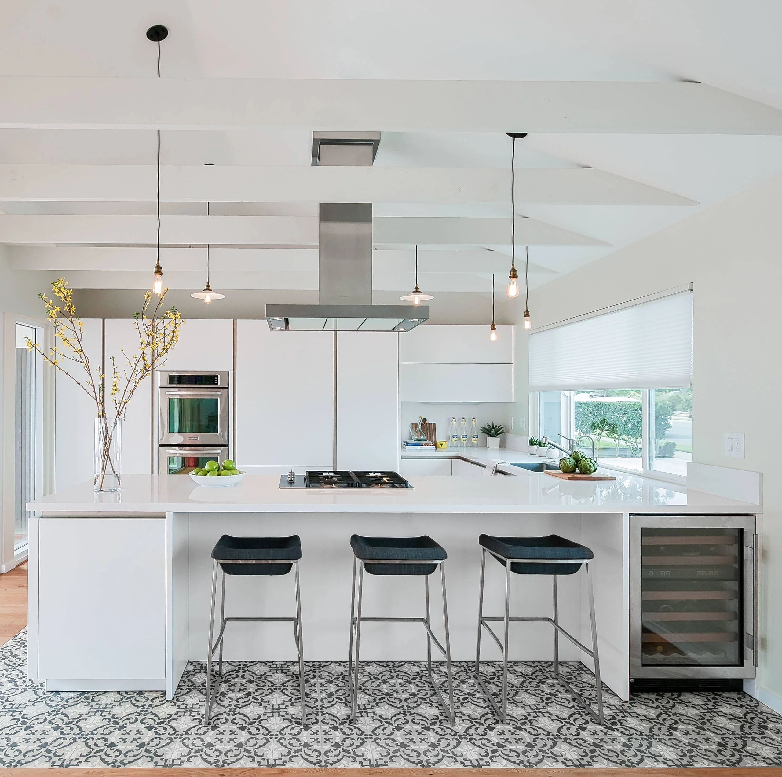 Modern luxury kitchen with sleek white cabinets, a large island with bar stools, pendant lighting